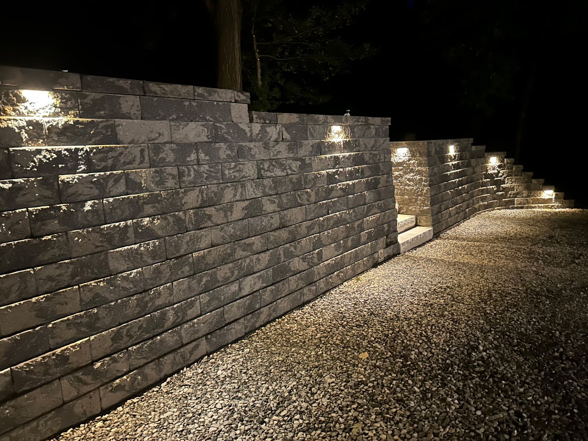 Stone retaining wall with pathway lit by small lights at night