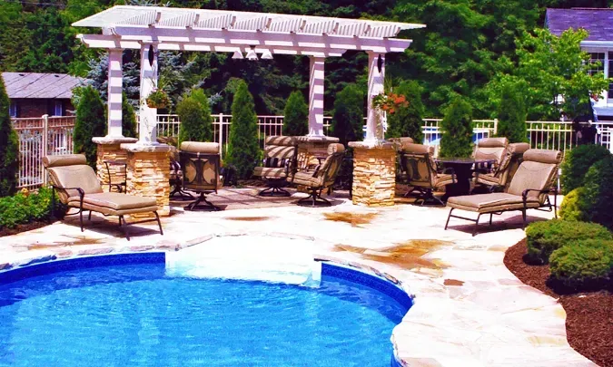 A swimming pool with a pergola and chairs around it