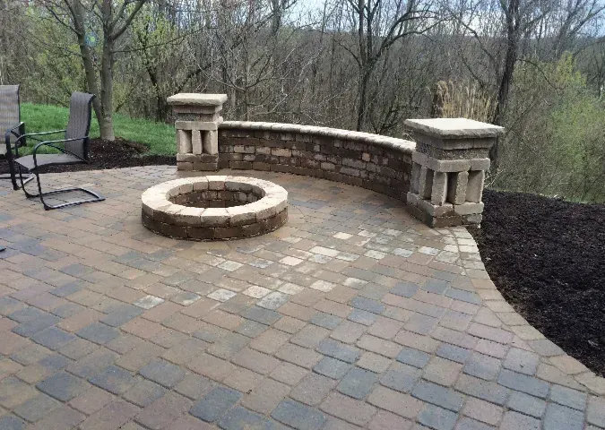 A fire pit is sitting on top of a brick patio.