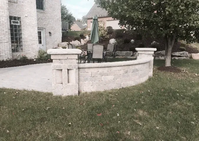 A patio with a brick wall and umbrella in front of a house.
