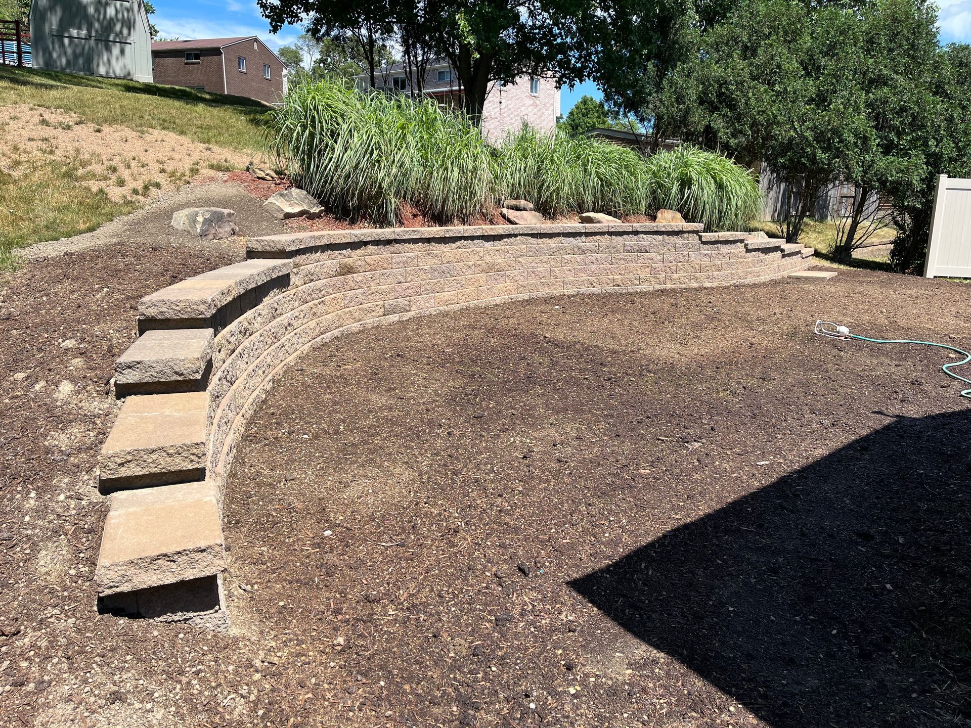 A stone wall with stairs leading up to it in a yard.