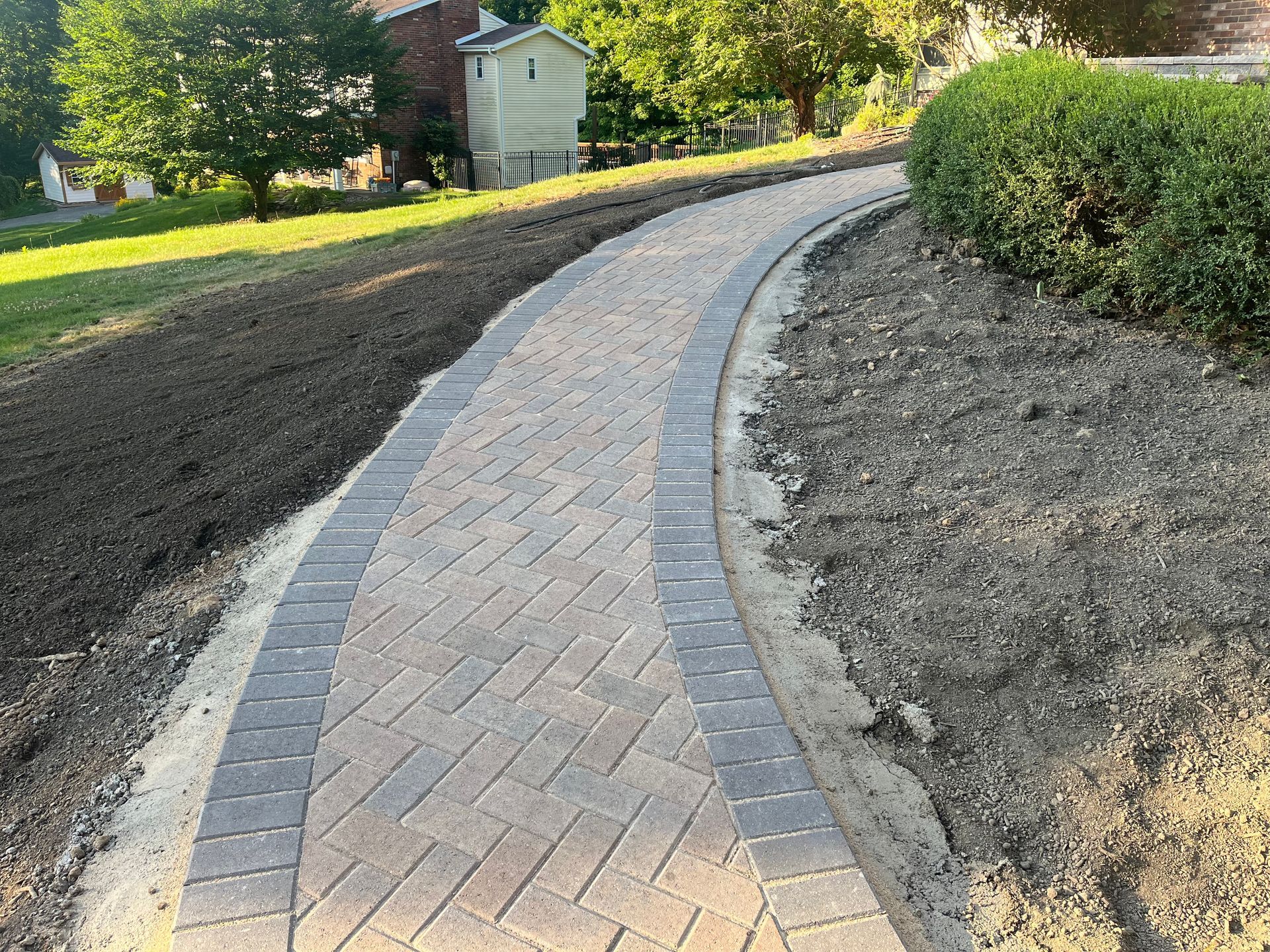 A brick walkway going through a lush green field.
