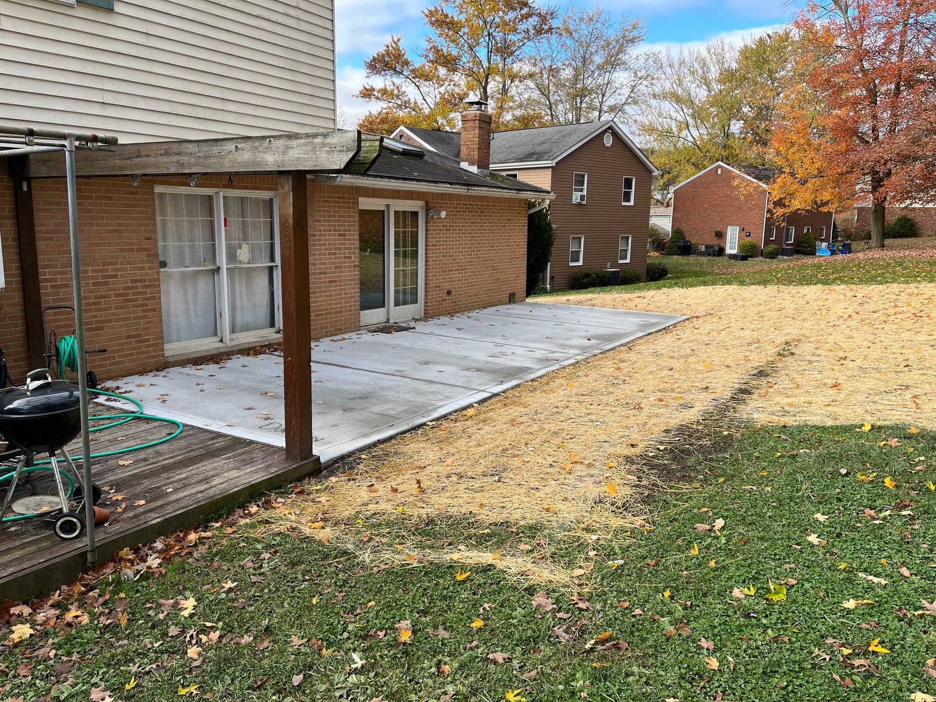 A brick house with a patio and a grill in the backyard.