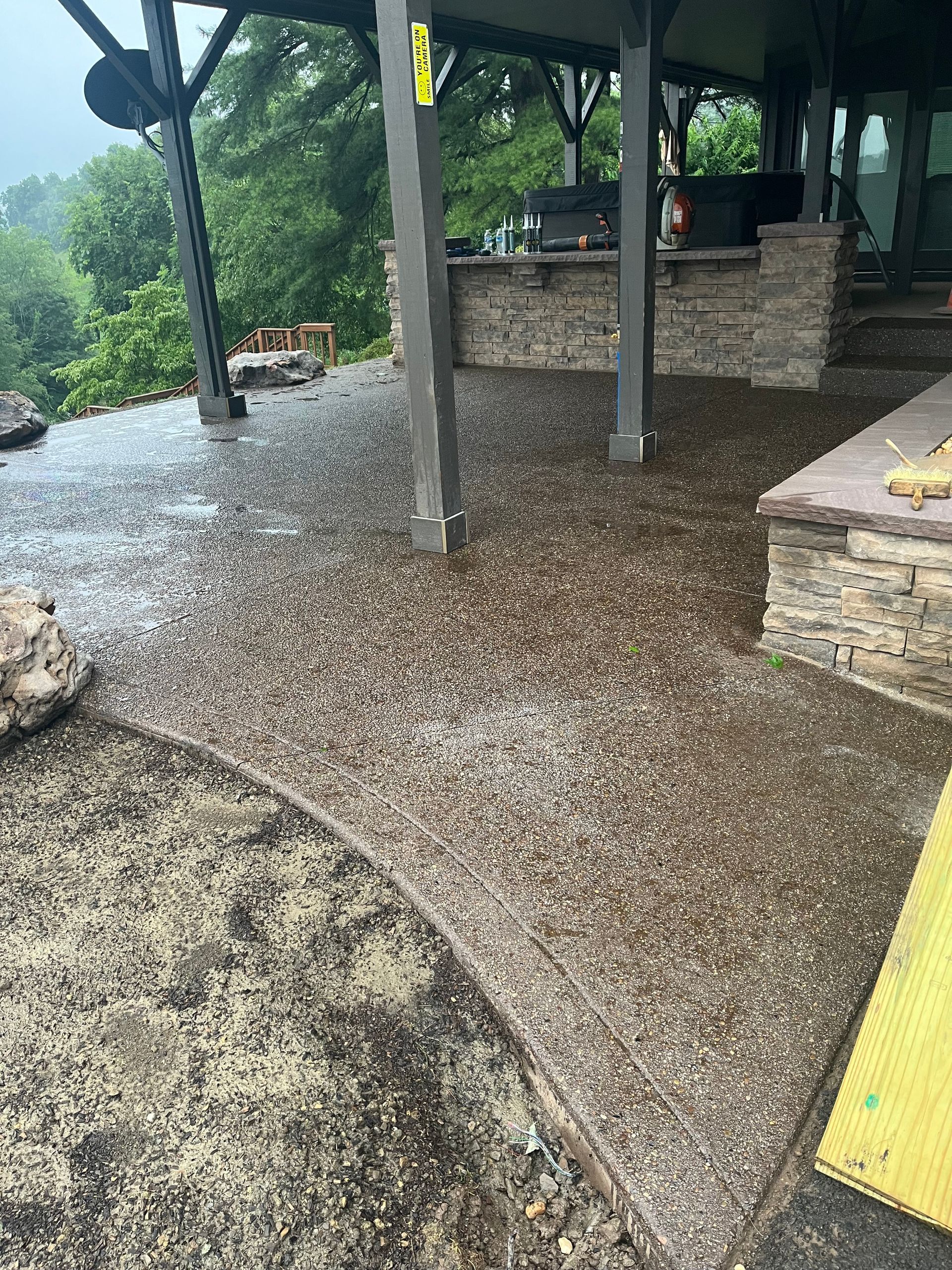 A patio with a concrete floor and a stone wall.