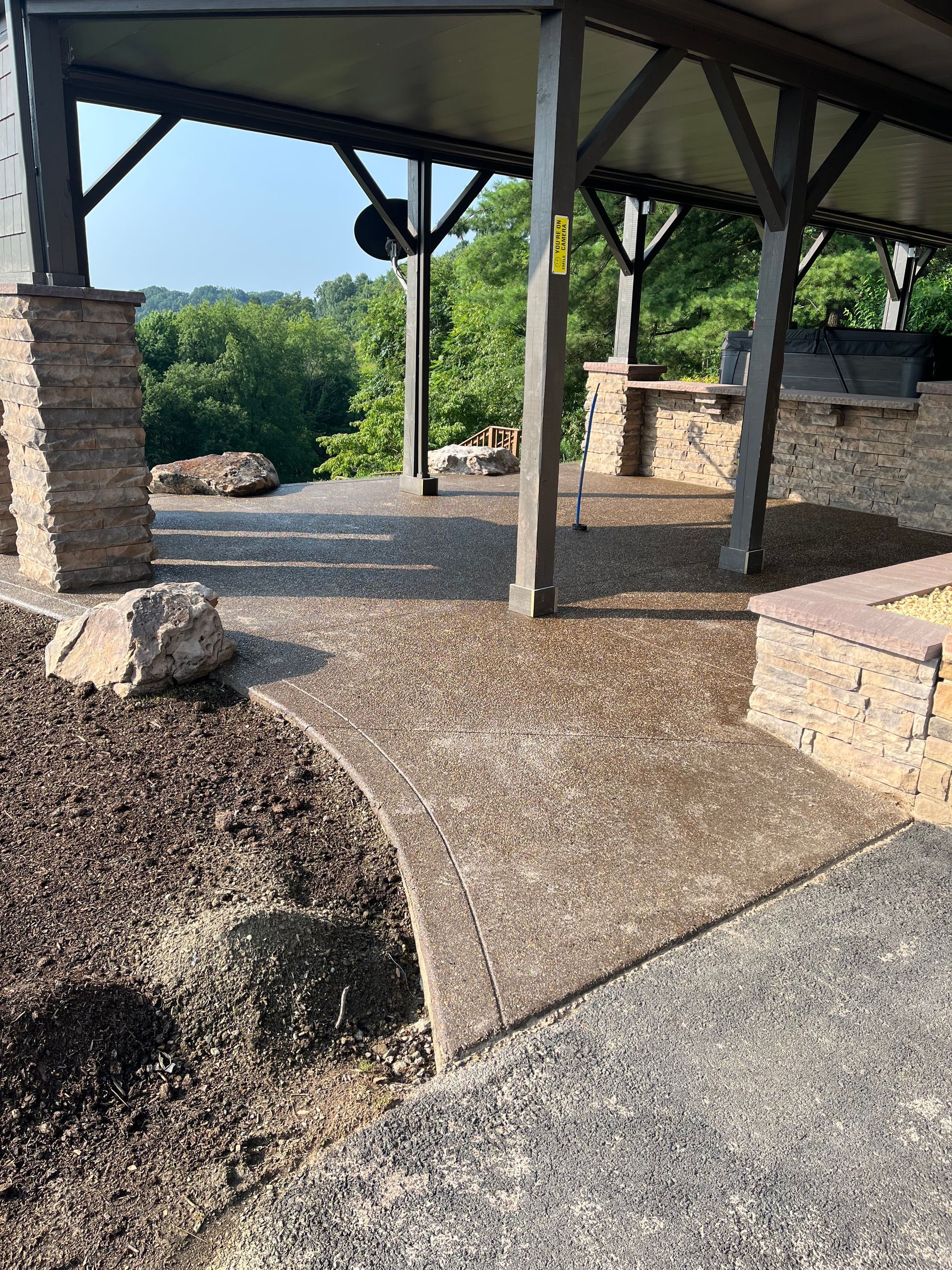 A patio with a covered area and a stone wall.