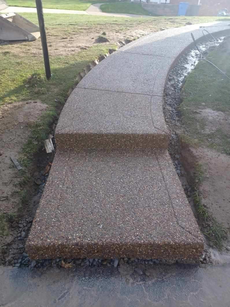 A concrete walkway with stairs leading up to it in a park.