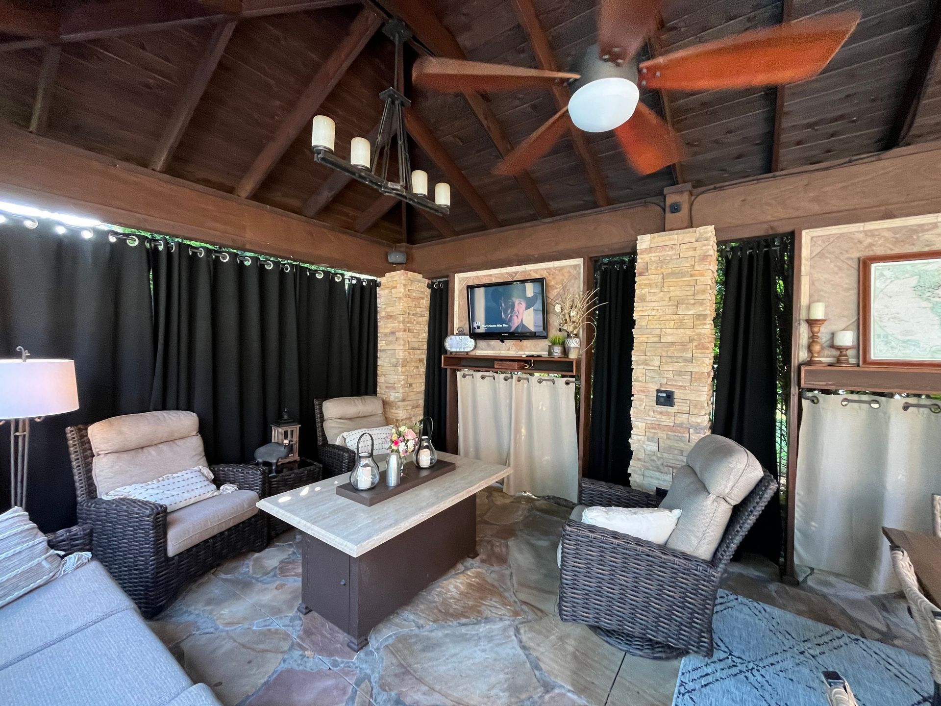 A living room with a couch, chairs, a table, and a ceiling fan.