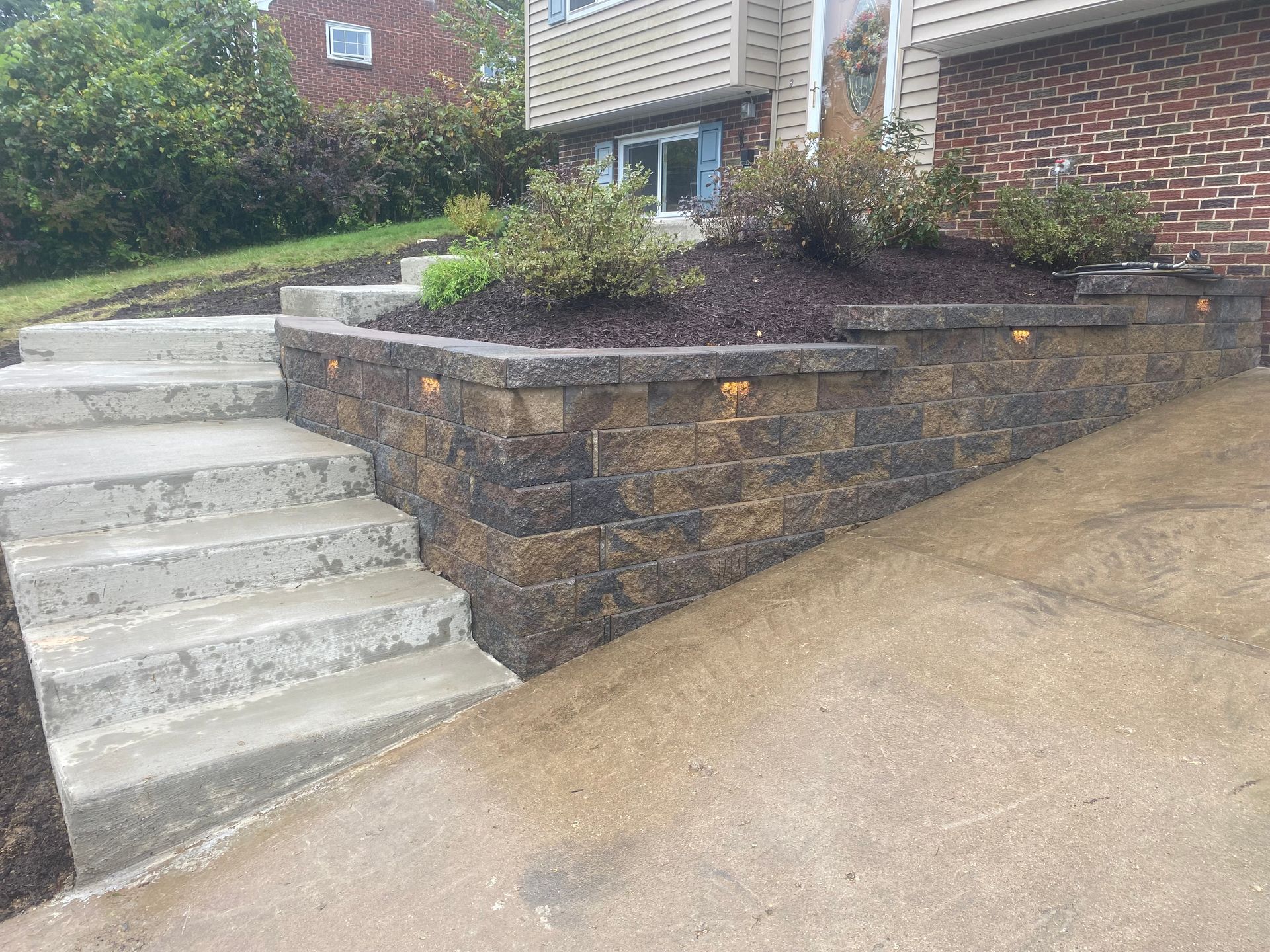 A stone wall with stairs leading up to a house.
