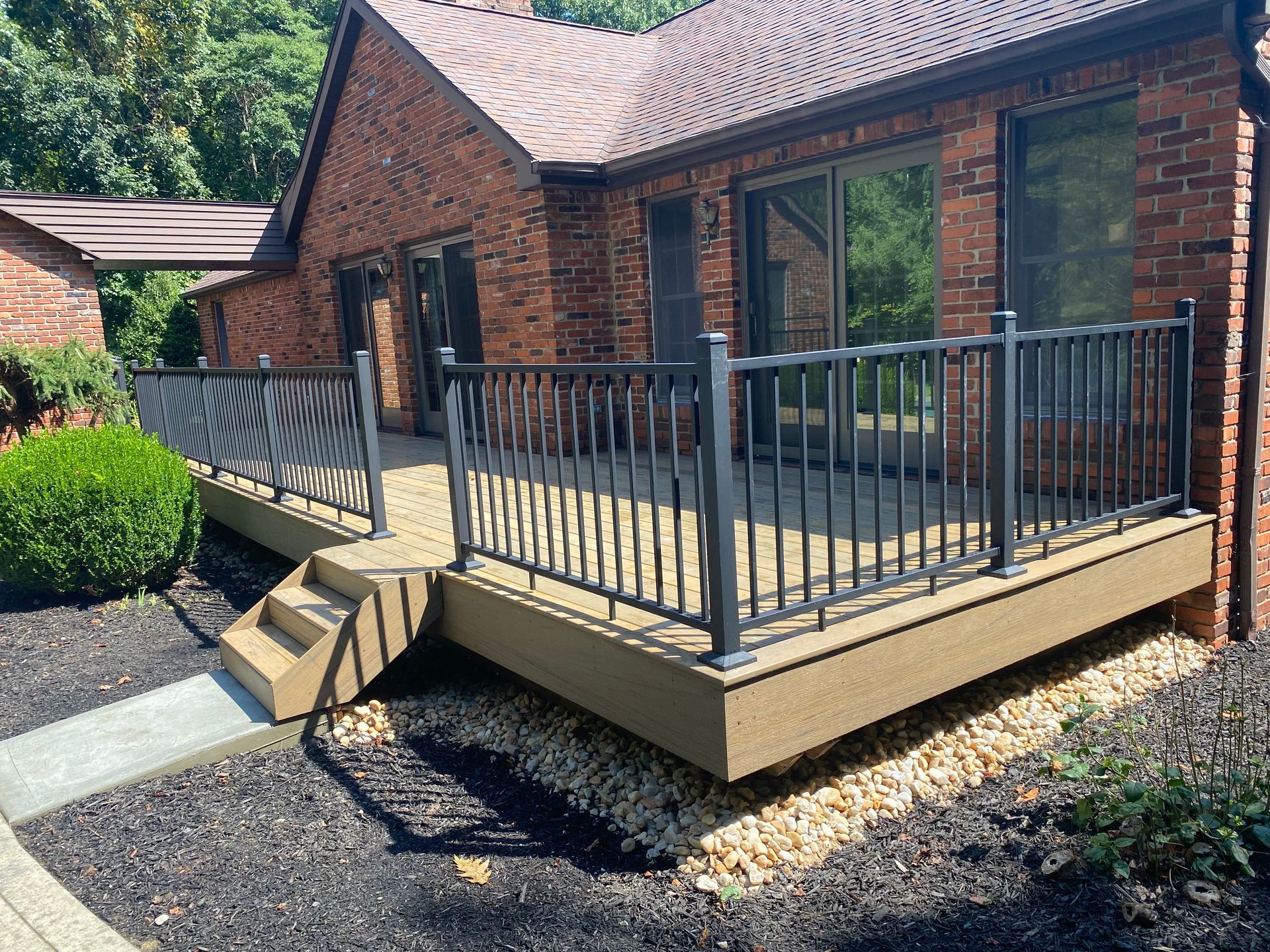 A brick house with a deck and stairs in front of it.