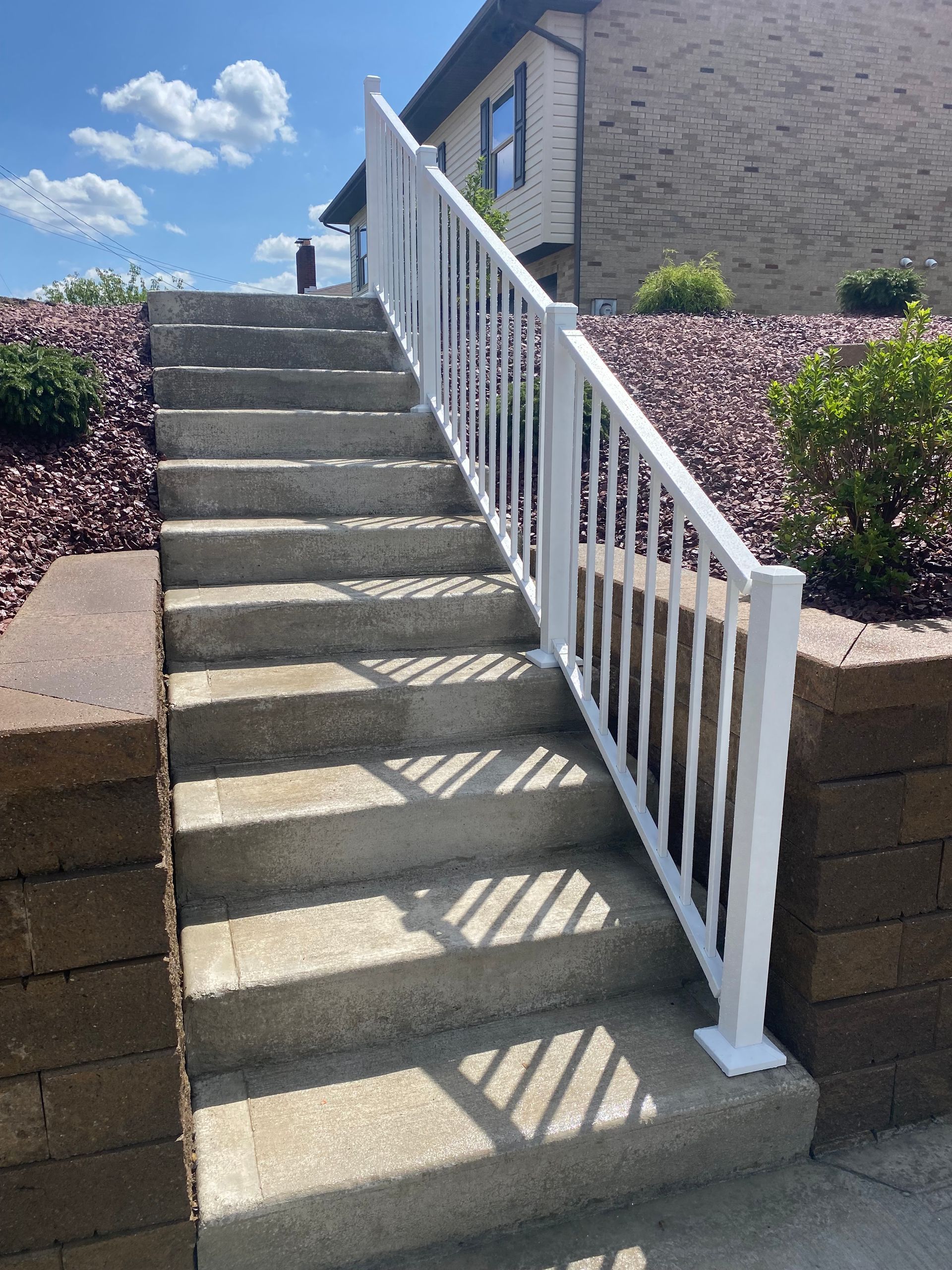 A set of stairs with a white railing leading up to a house