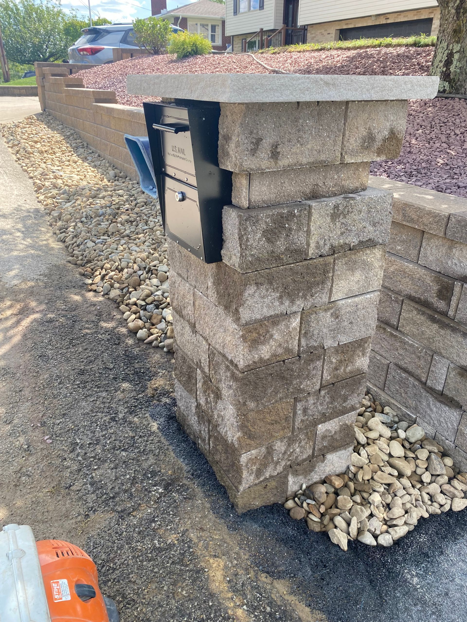 A mailbox is sitting on top of a brick pillar.