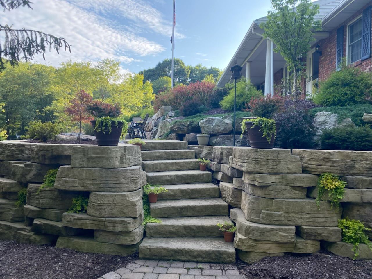 A stone wall with stairs leading up to a house.