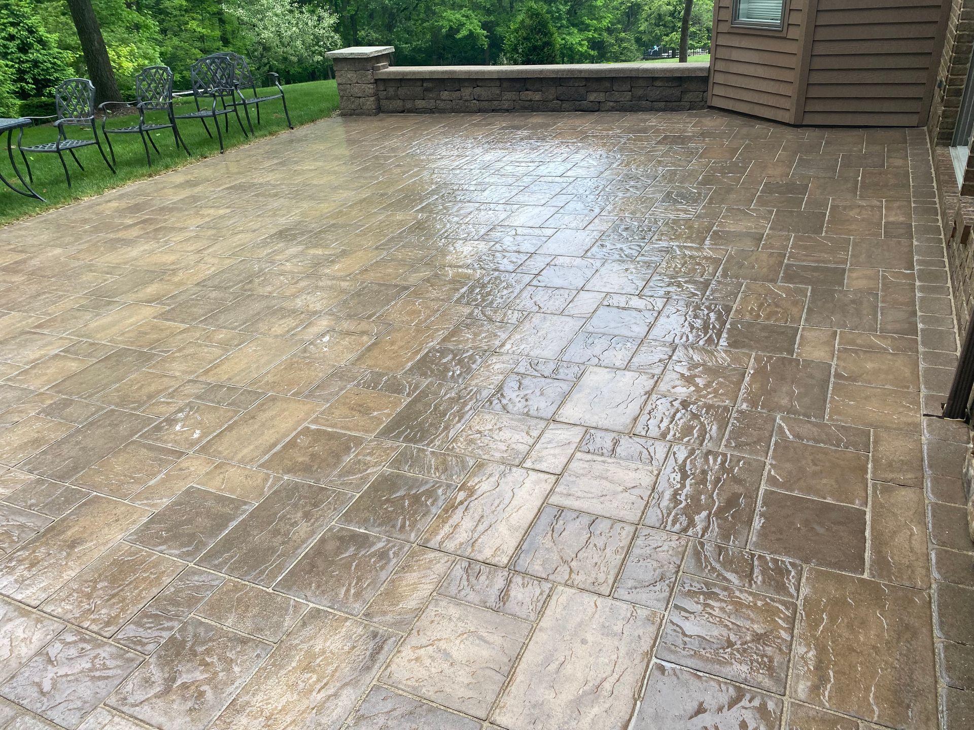 A patio with a brick wall and chairs in the background.