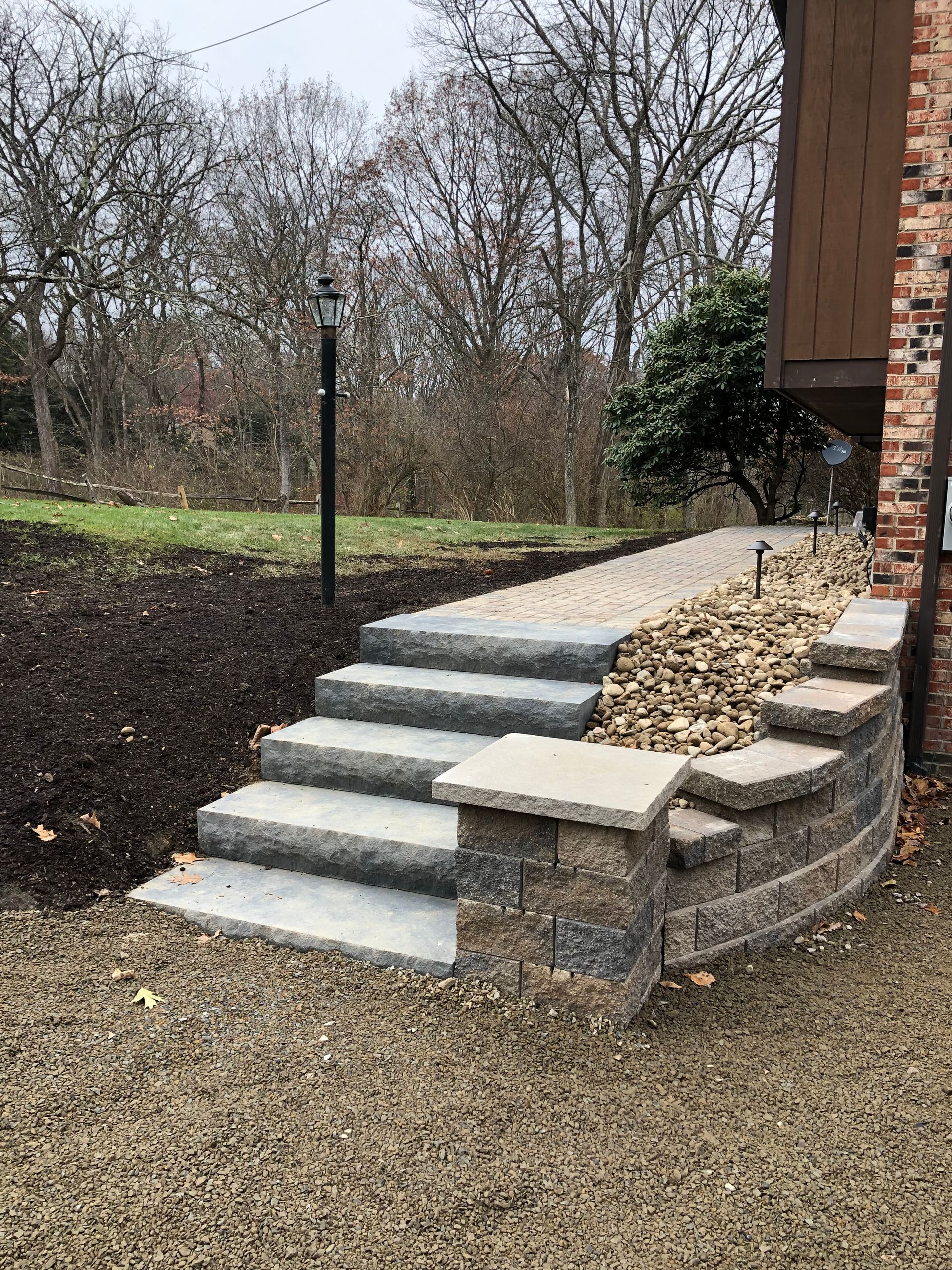 A set of stairs leading up to a stone wall next to a house.