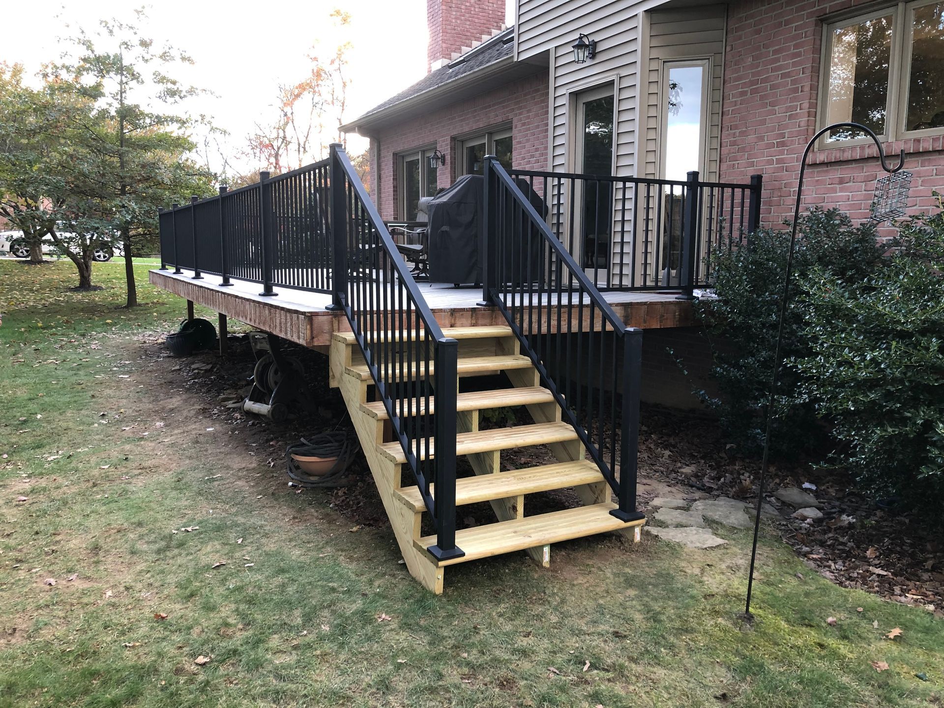 A wooden deck with stairs leading up to it in front of a house.