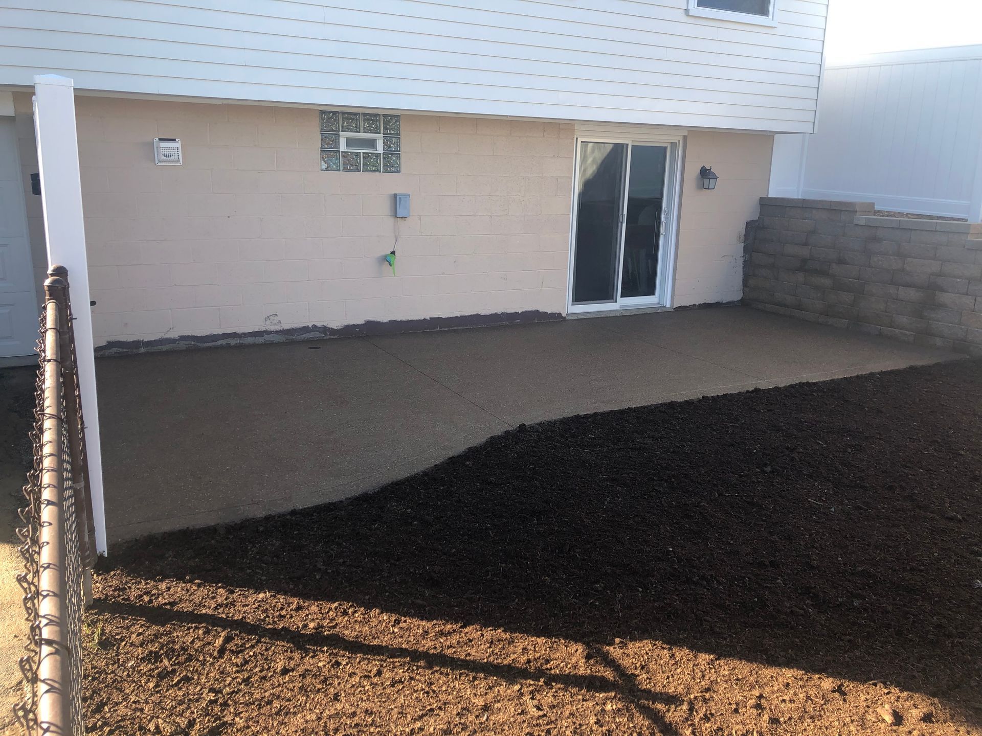 The backyard of a house with a patio and a fence.