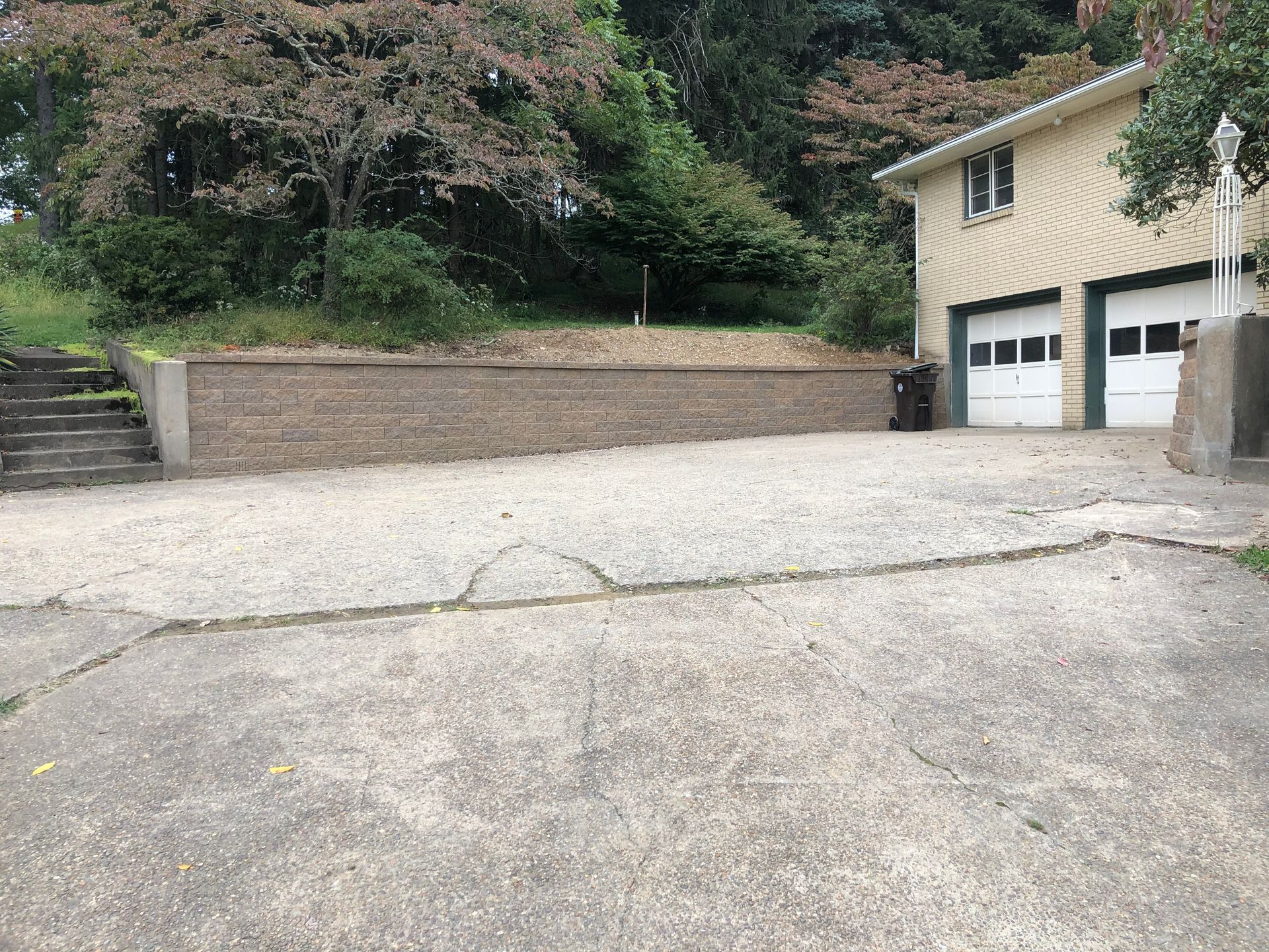 A concrete driveway leading to a house with two garage doors.