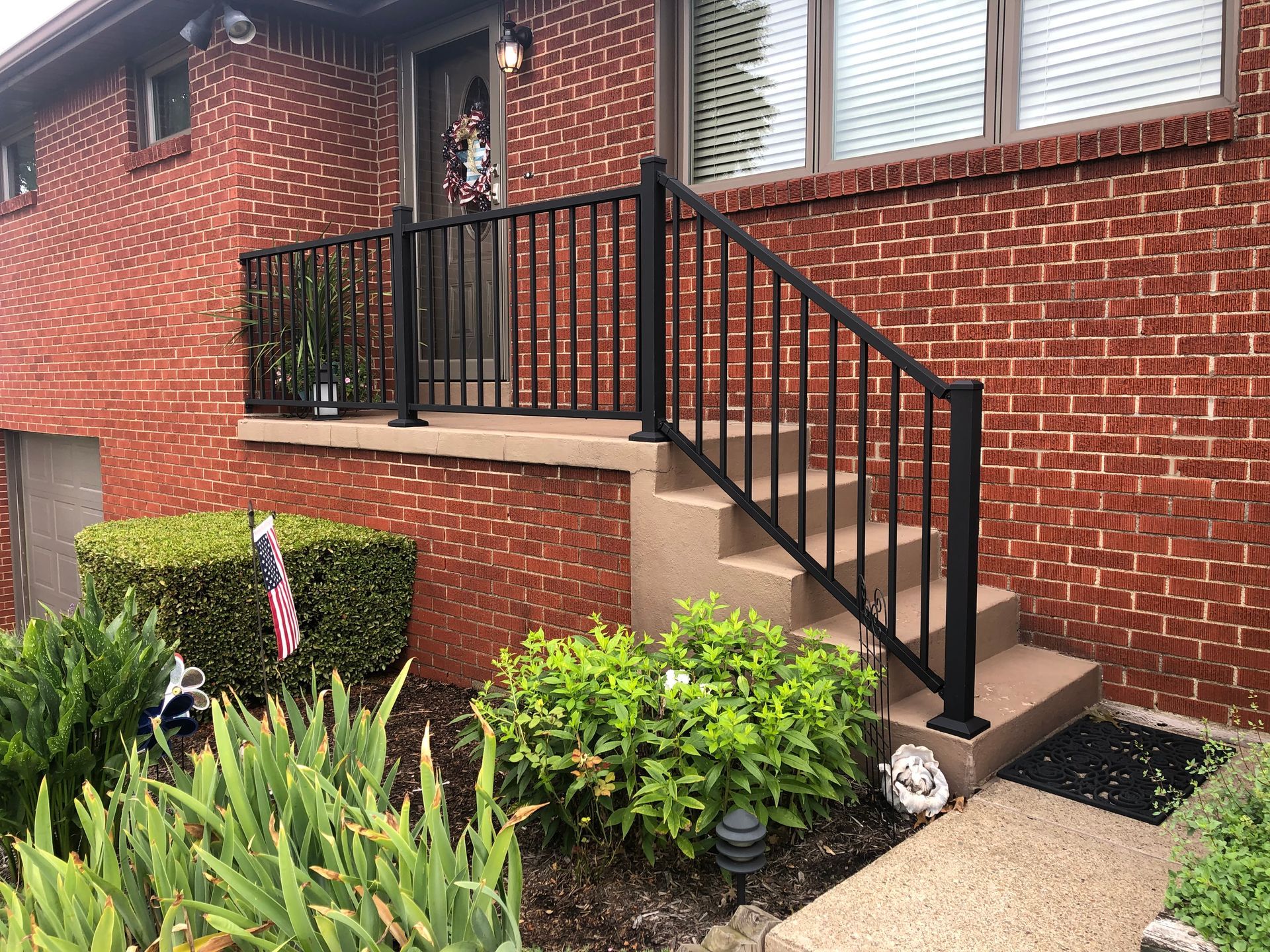 A brick house with a black railing and stairs.