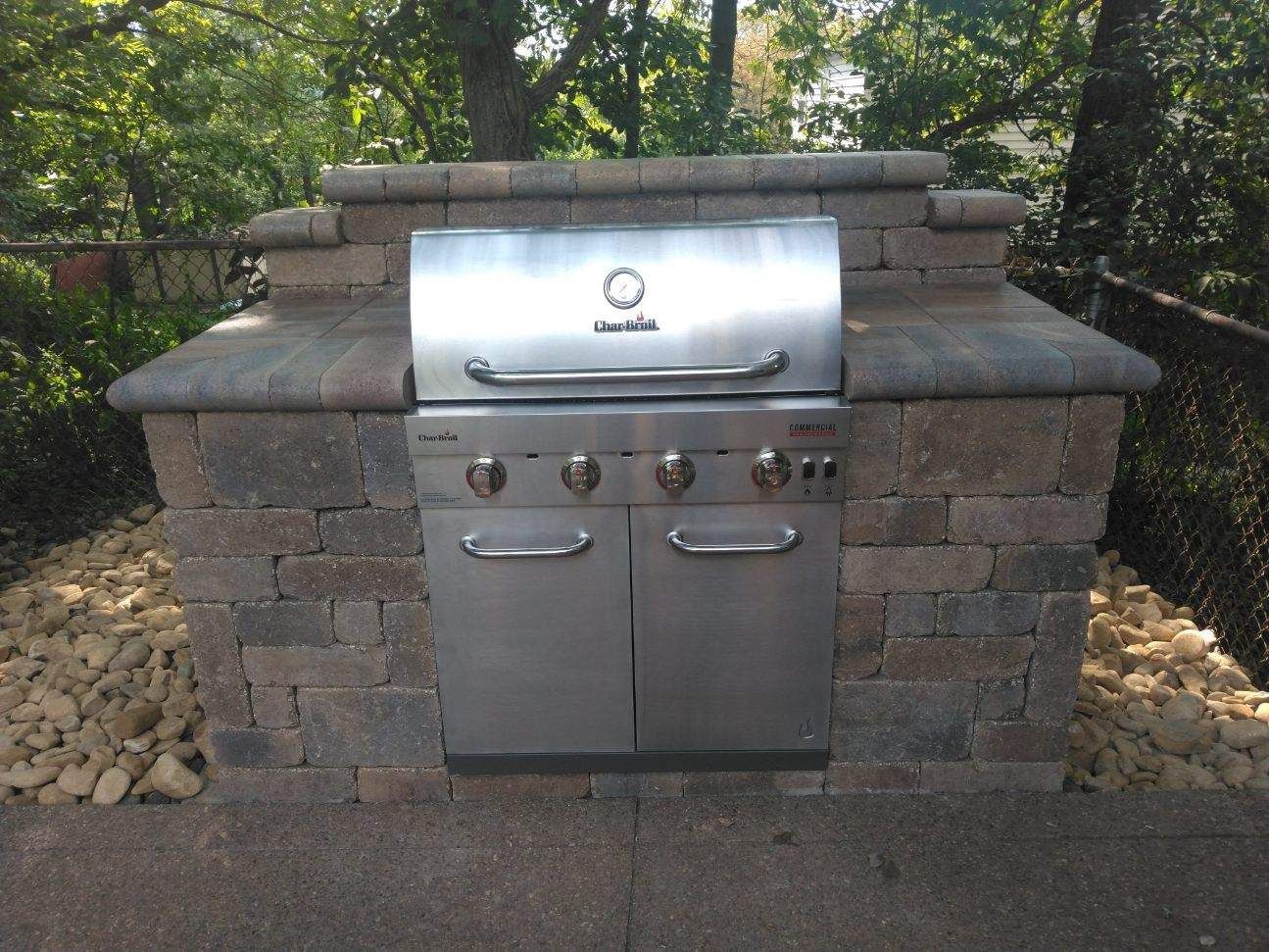 A stainless steel grill is built into a brick wall
