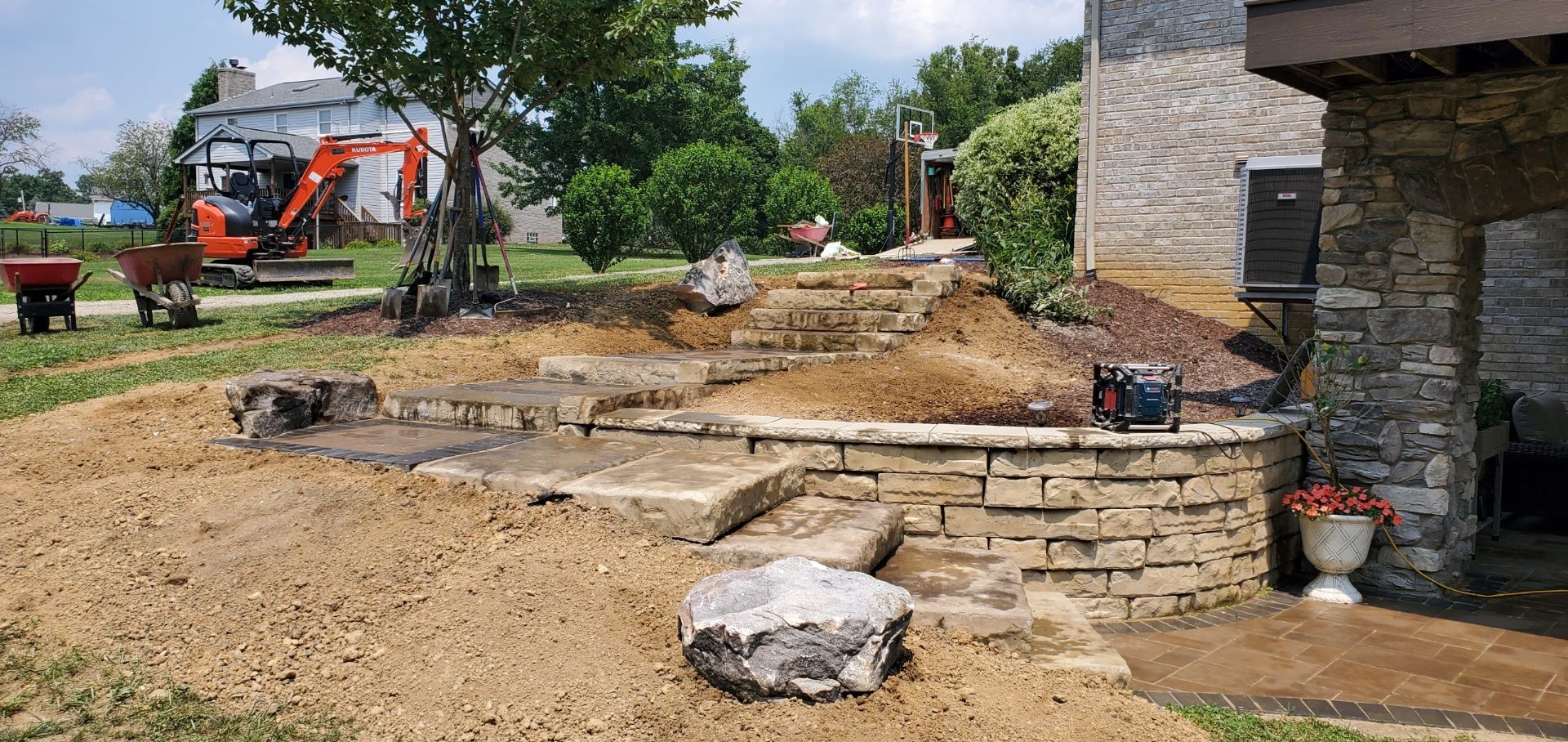 A stone wall is being built in the backyard of a house.