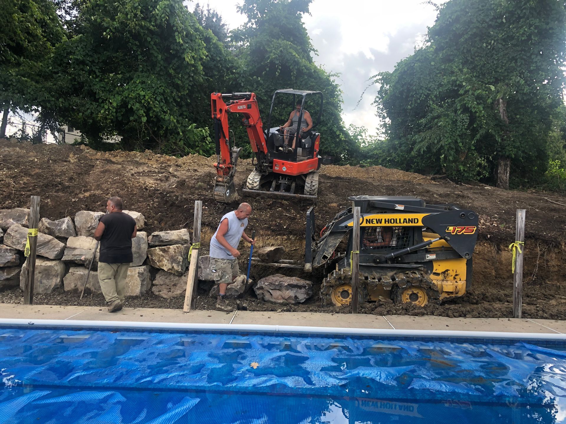 A couple of men are standing next to a swimming pool.