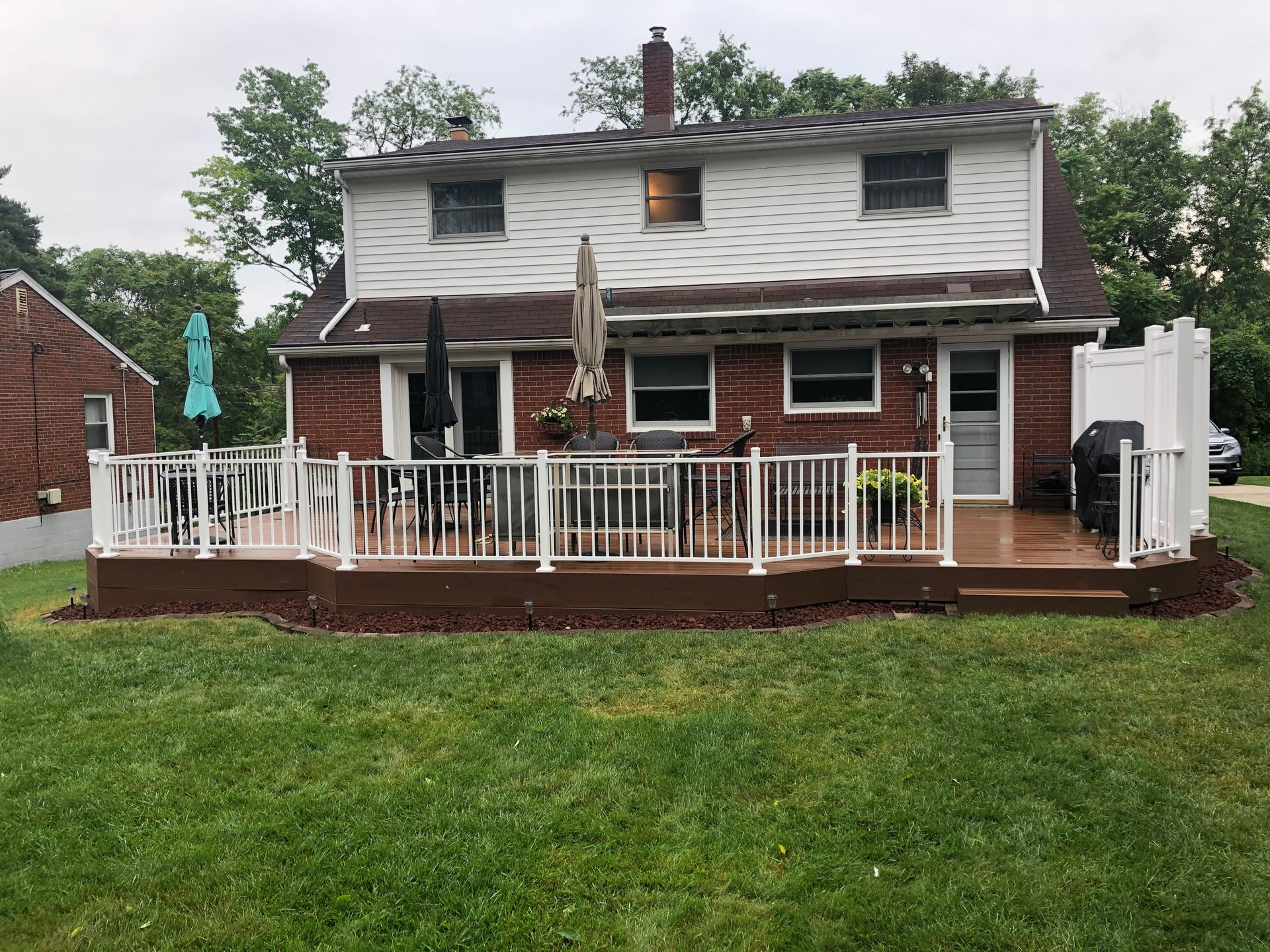 The back of a house with a large deck and a white railing.