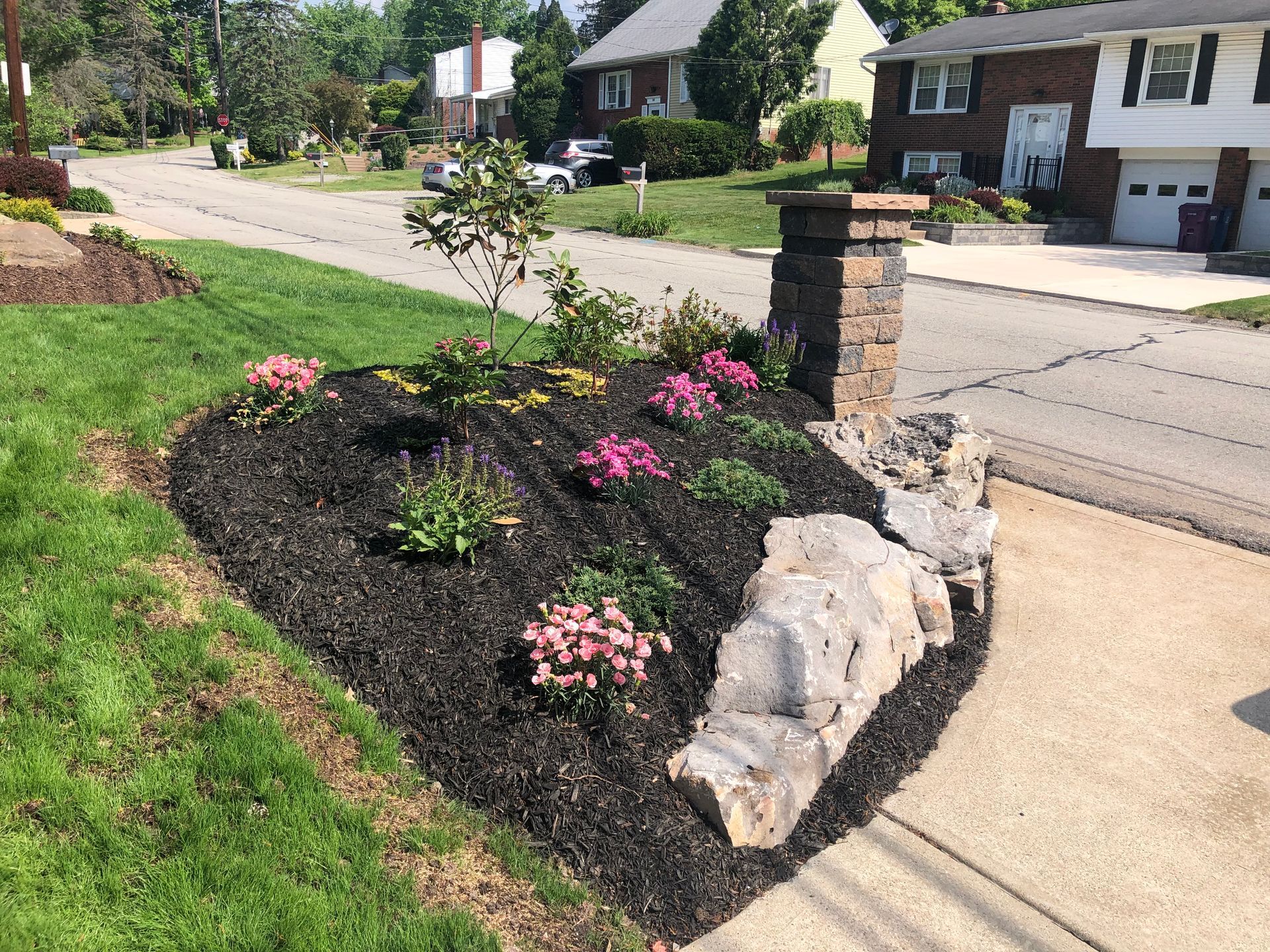 A garden with flowers and mulch in front of a house.