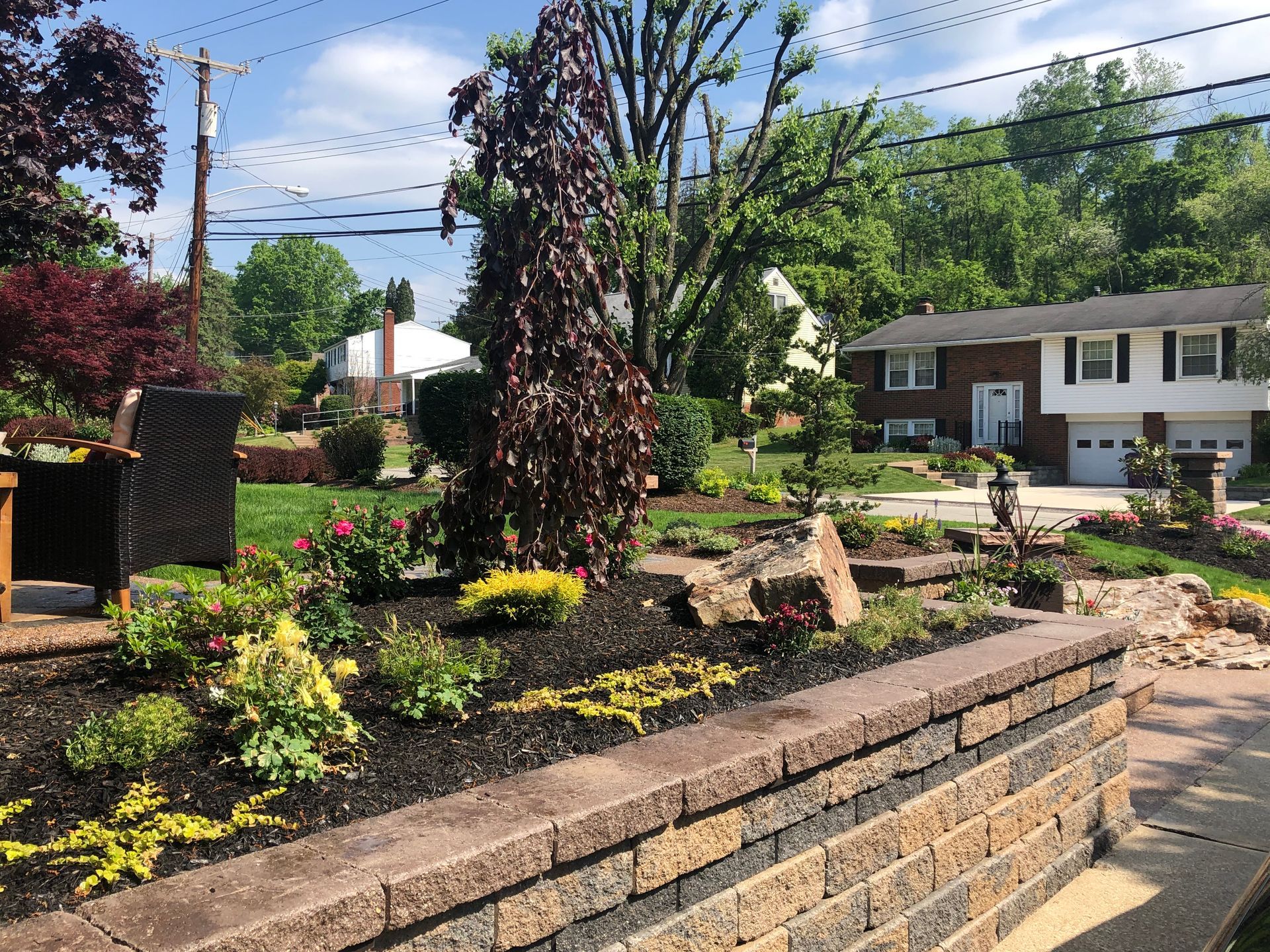 A brick wall surrounds a garden in front of a house.