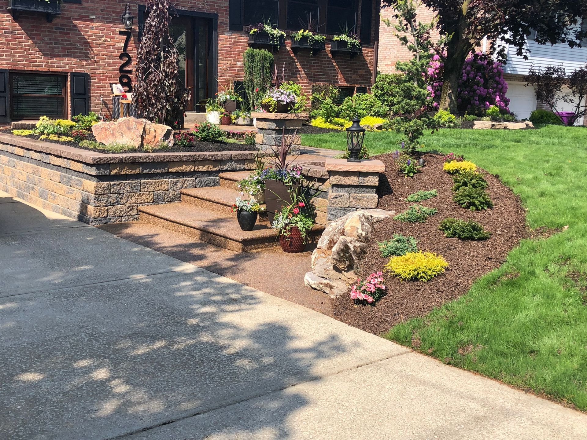 A brick house with a lush green lawn and a stone walkway leading to it.