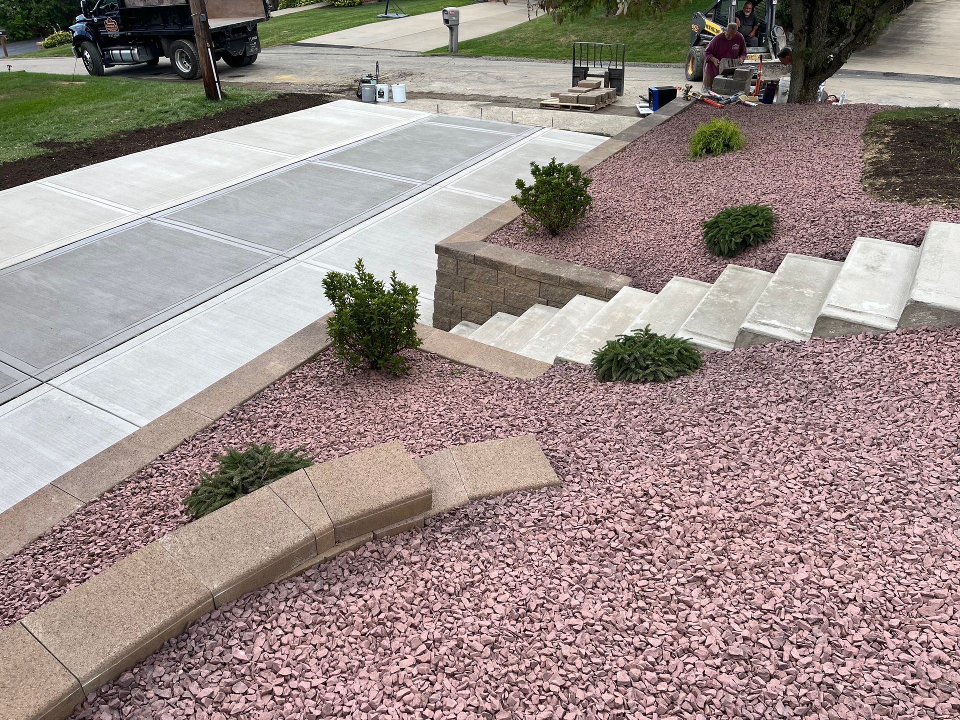 A concrete driveway with stairs and pink gravel in front of a house.