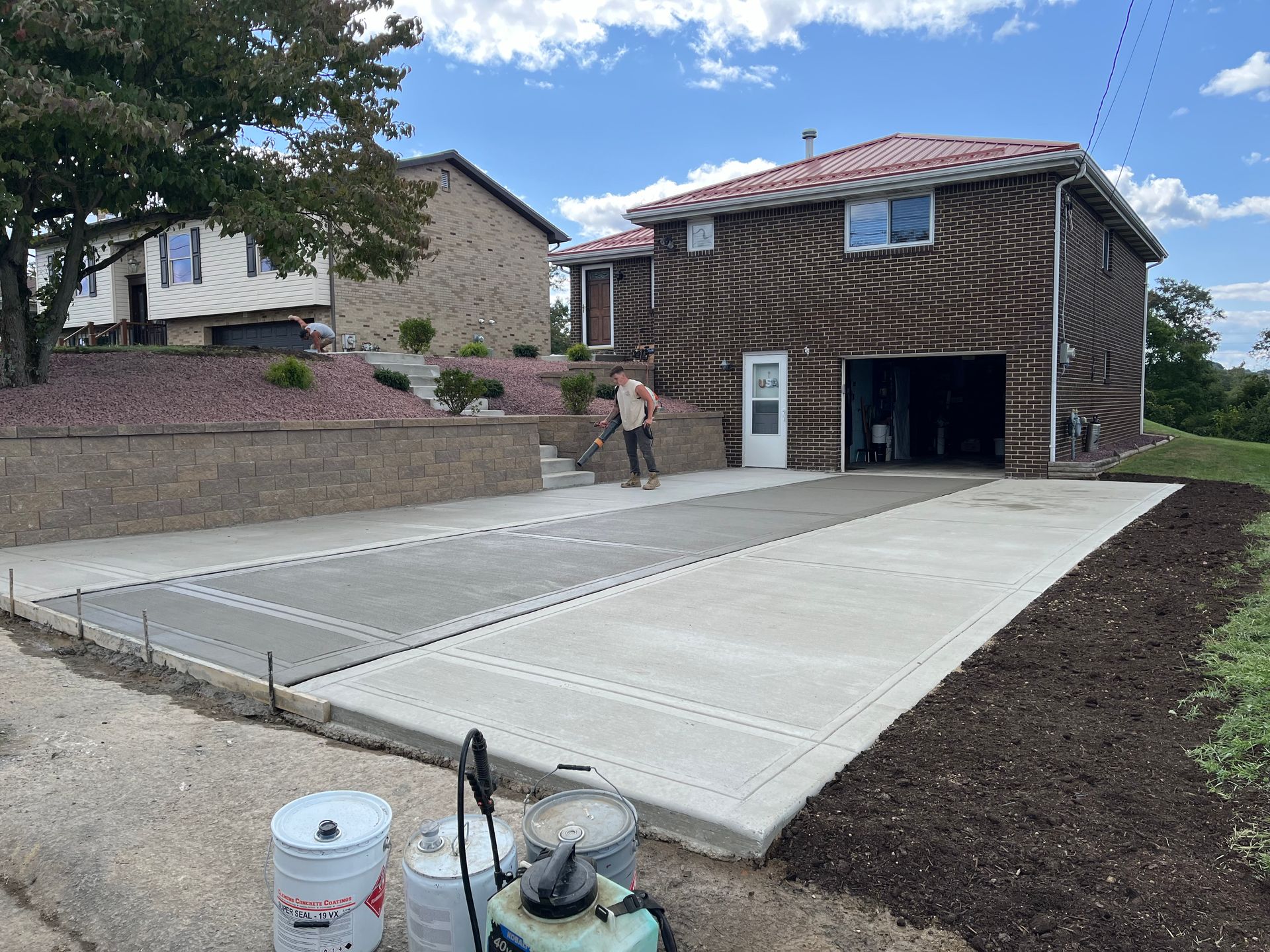 A man is working on a concrete driveway in front of a house.