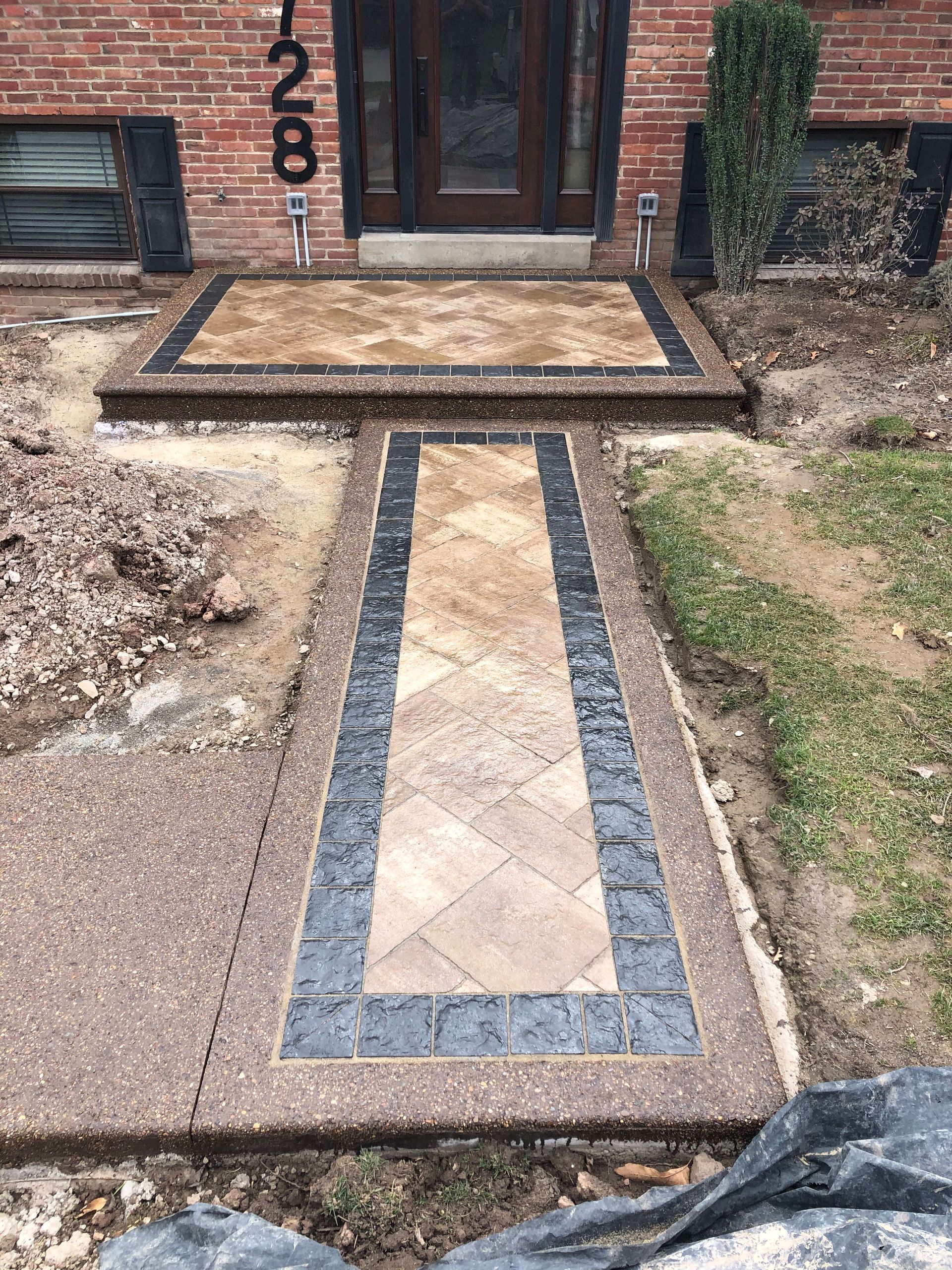 A walkway is being built in front of a brick house.