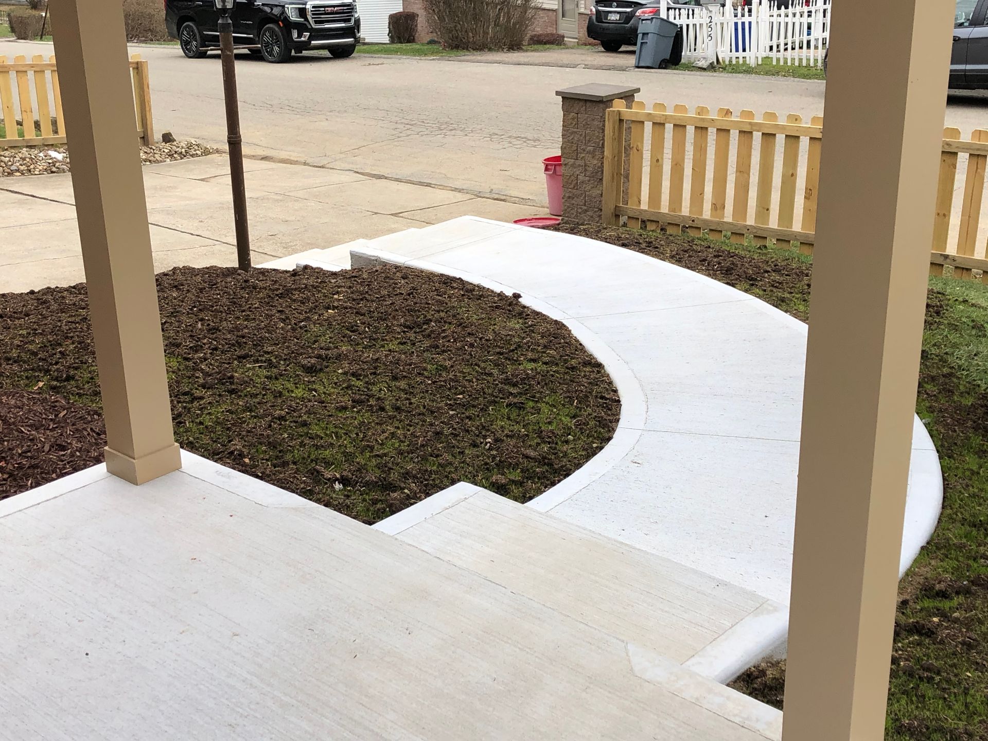 A concrete walkway with a wooden fence in the background.