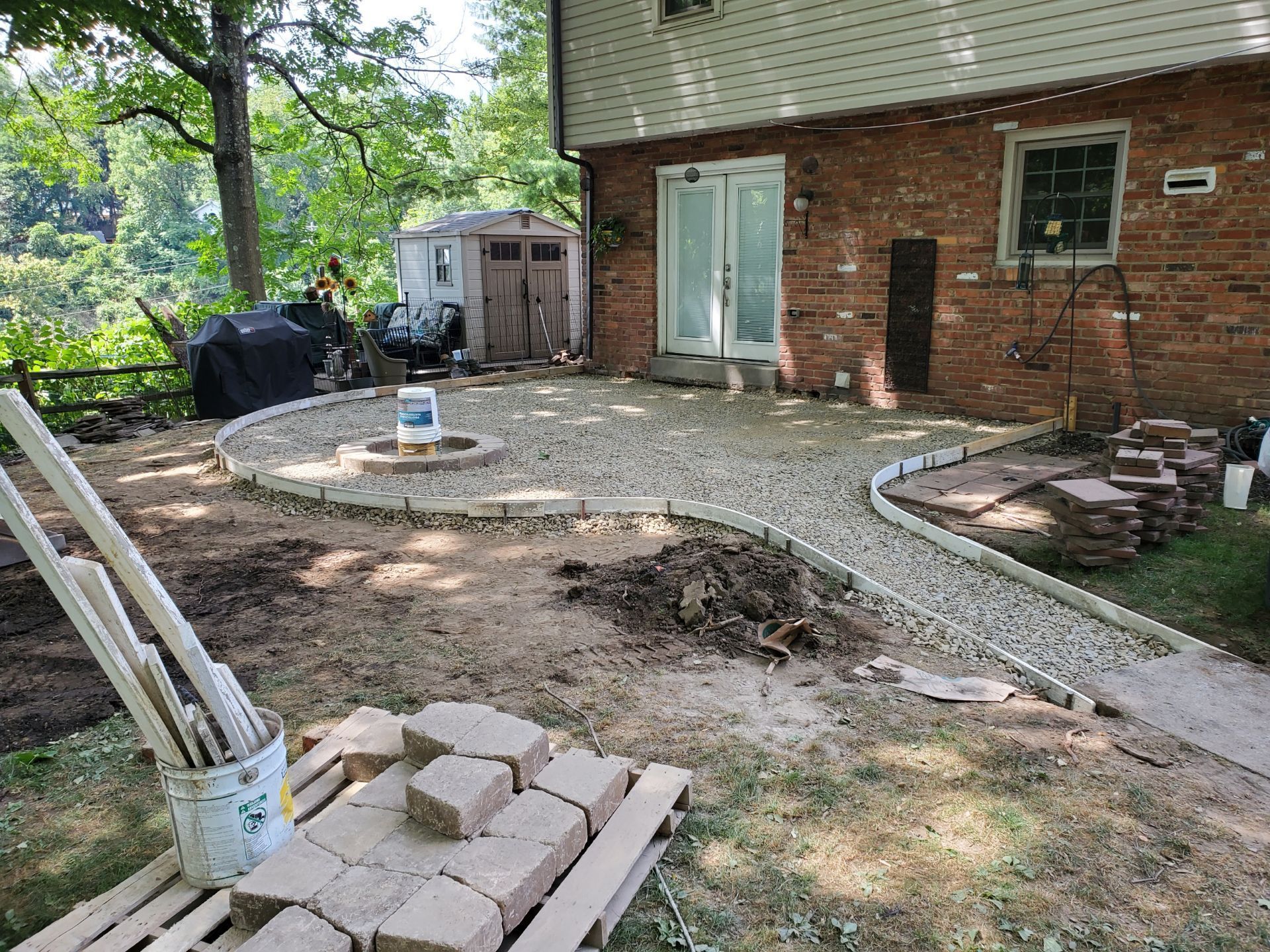 A brick house with a patio being built in front of it.