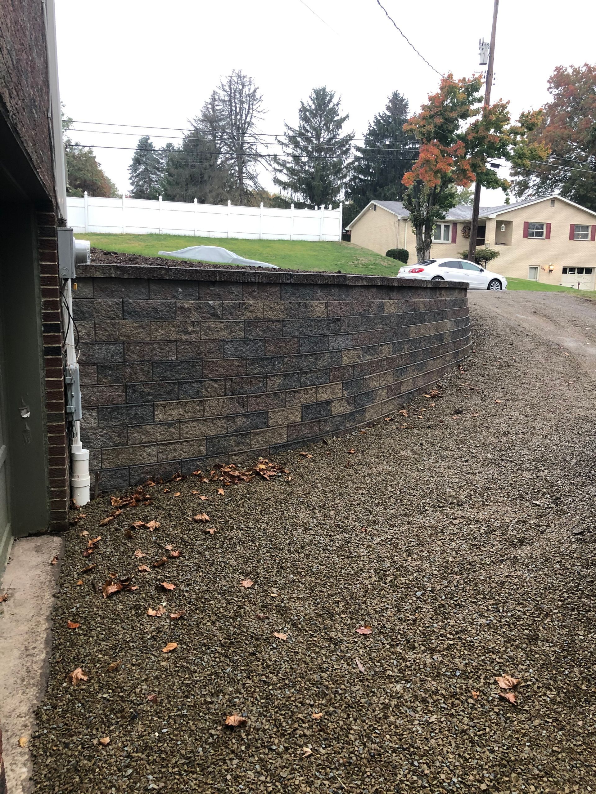 A gravel driveway leading to a garage with a brick wall in the background.
