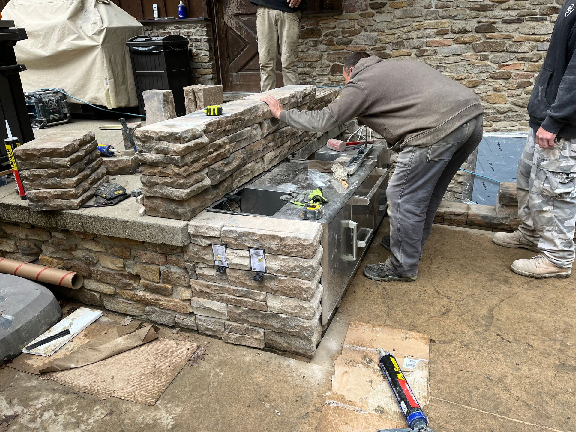 A man is working on a stone wall in front of a stone wall.
