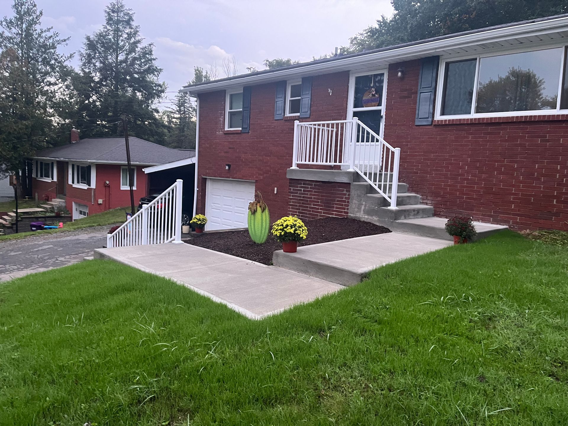 A red brick house with a white railing and stairs in front of it.