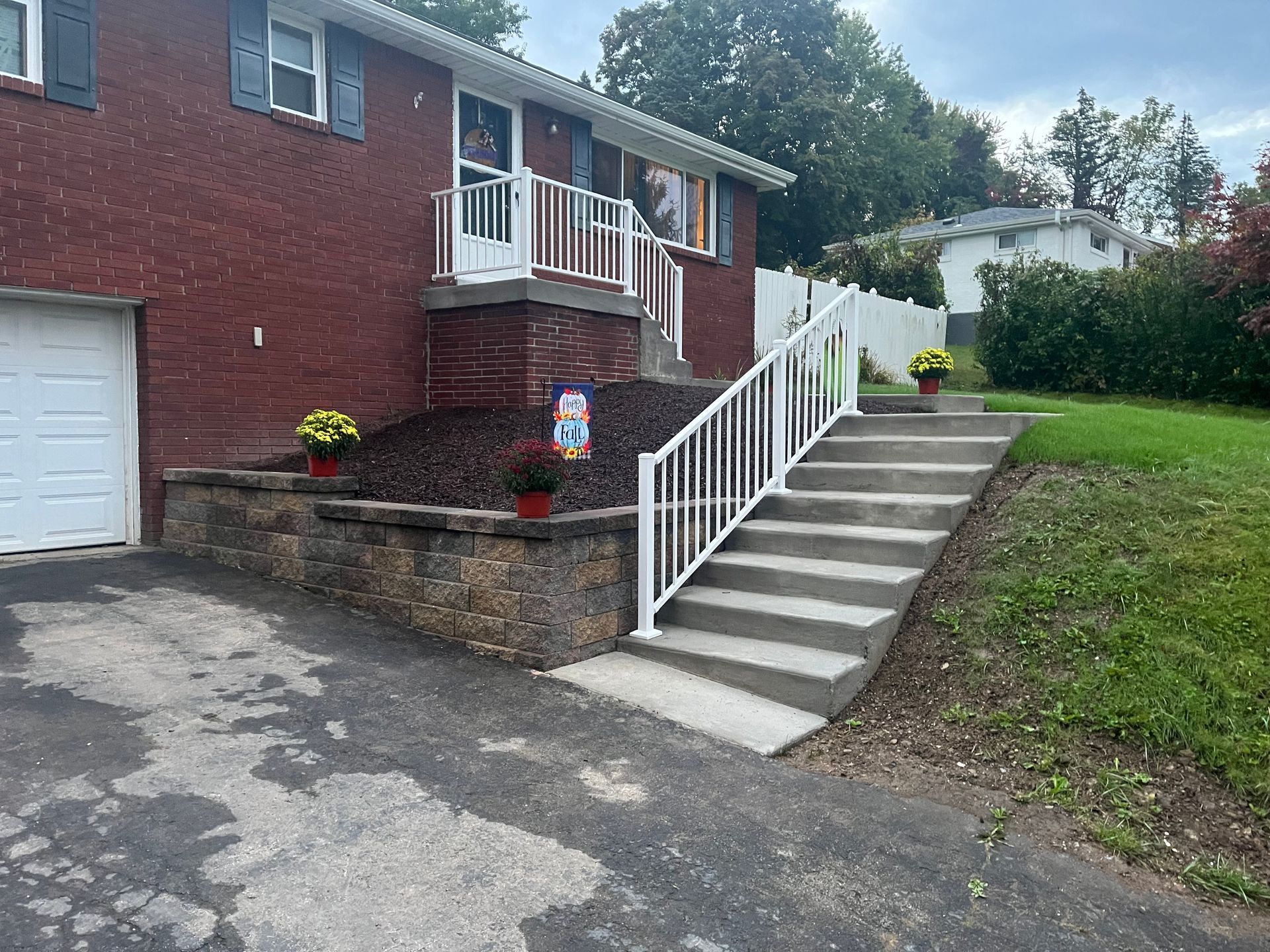A brick house with a white railing and stairs leading up to it.