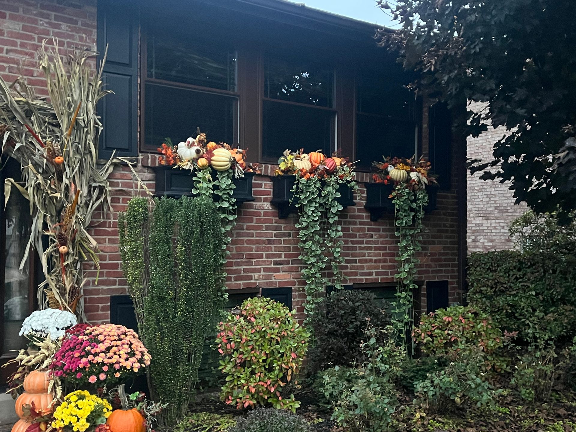A brick house with flowers and pumpkins in front of it