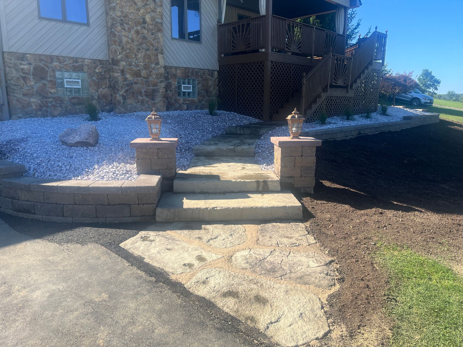 A stone walkway leading to a house with stairs leading up to it.