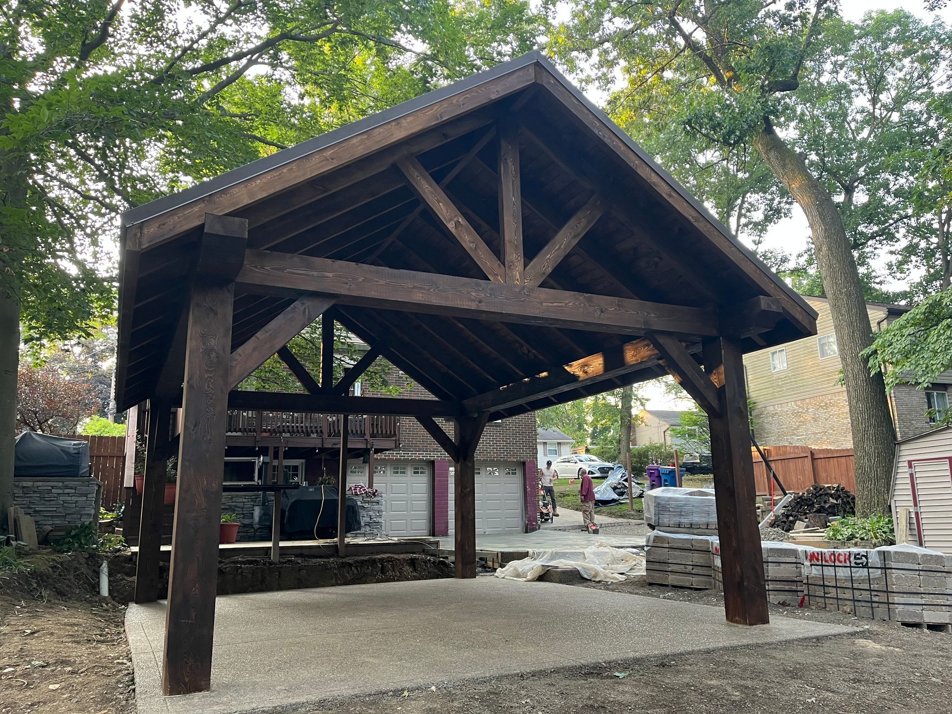 A wooden pavilion is being built in the backyard of a house.
