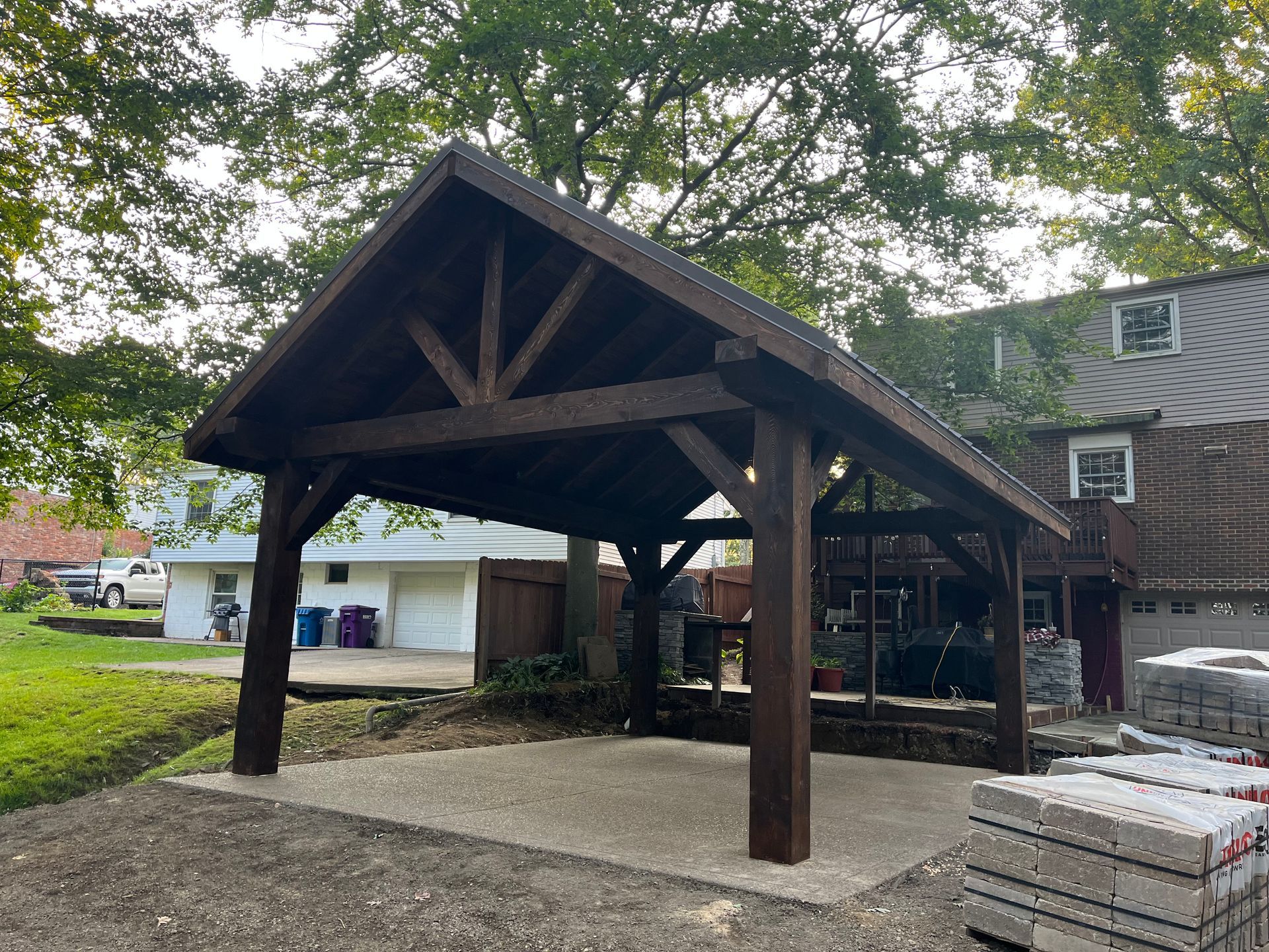 A wooden pavilion is sitting in front of a house.