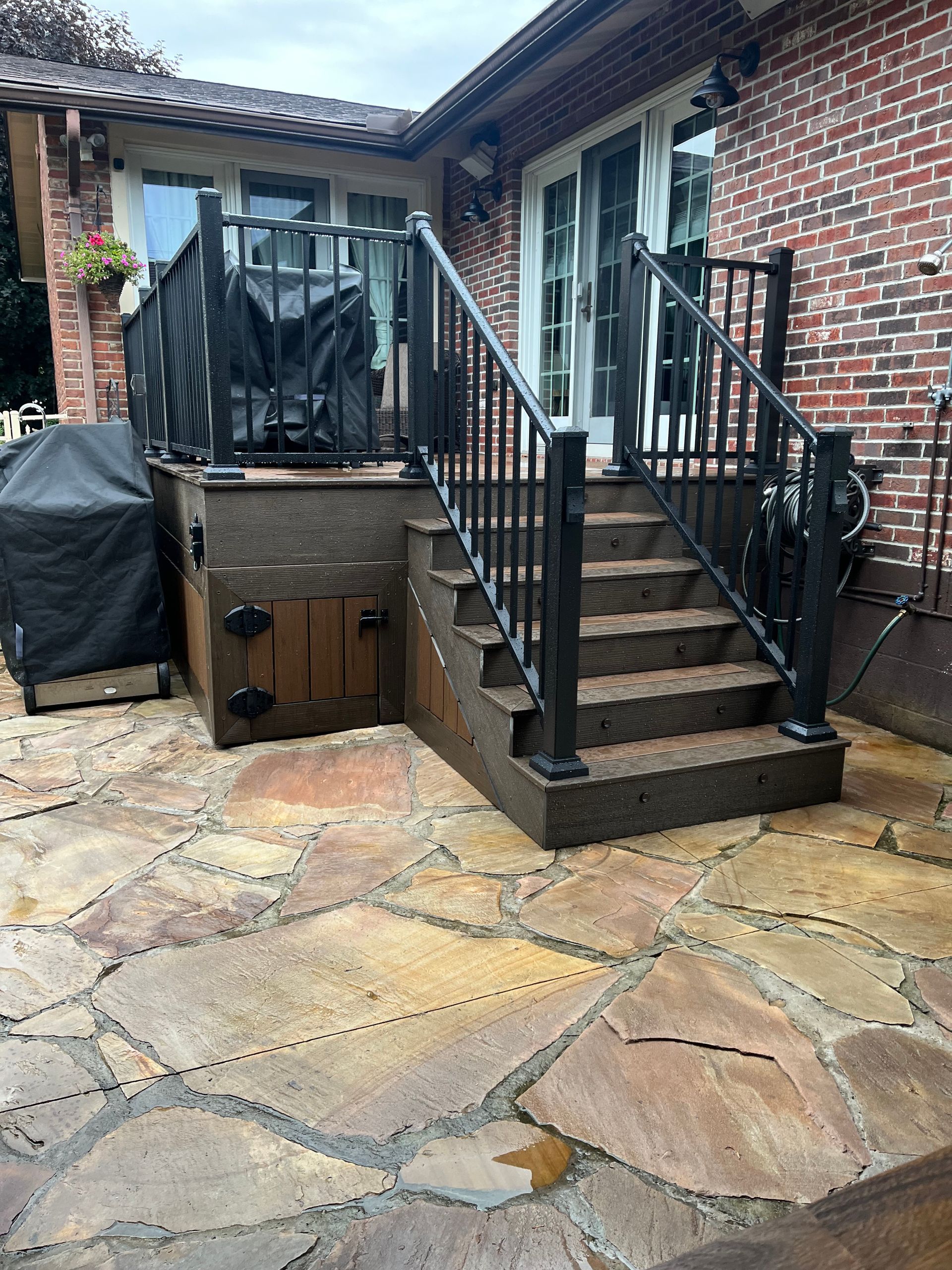 A brick house with a stone patio and stairs leading up to it.
