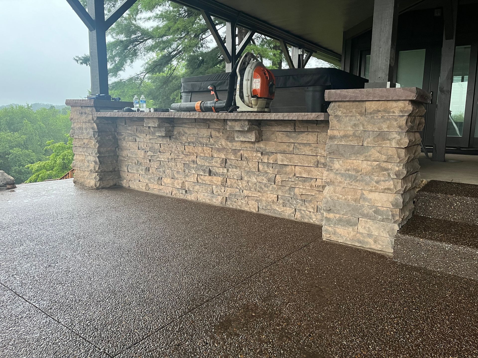 A patio with a brick wall and a grill on it.