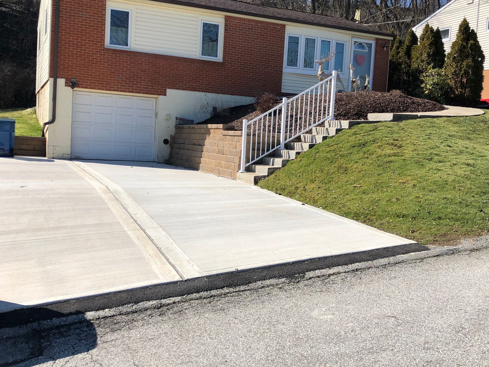 A house with a concrete driveway and stairs in front of it.