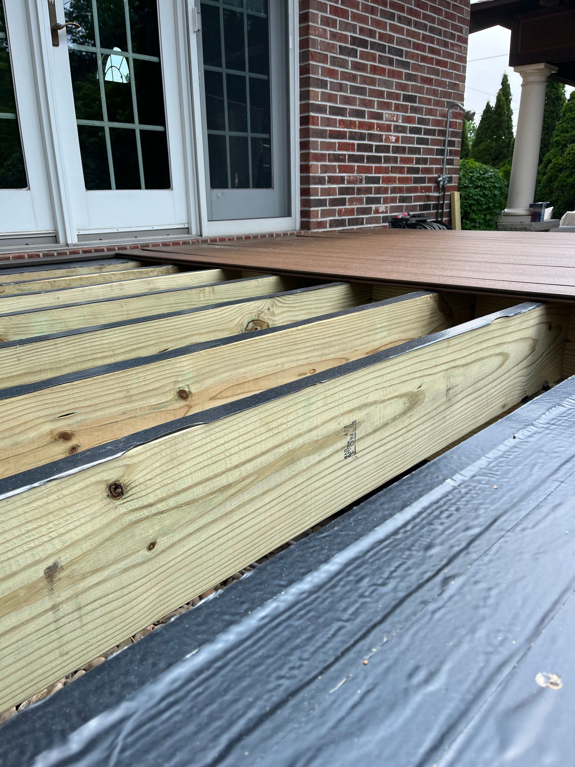 A wooden deck is being built in front of a brick building.