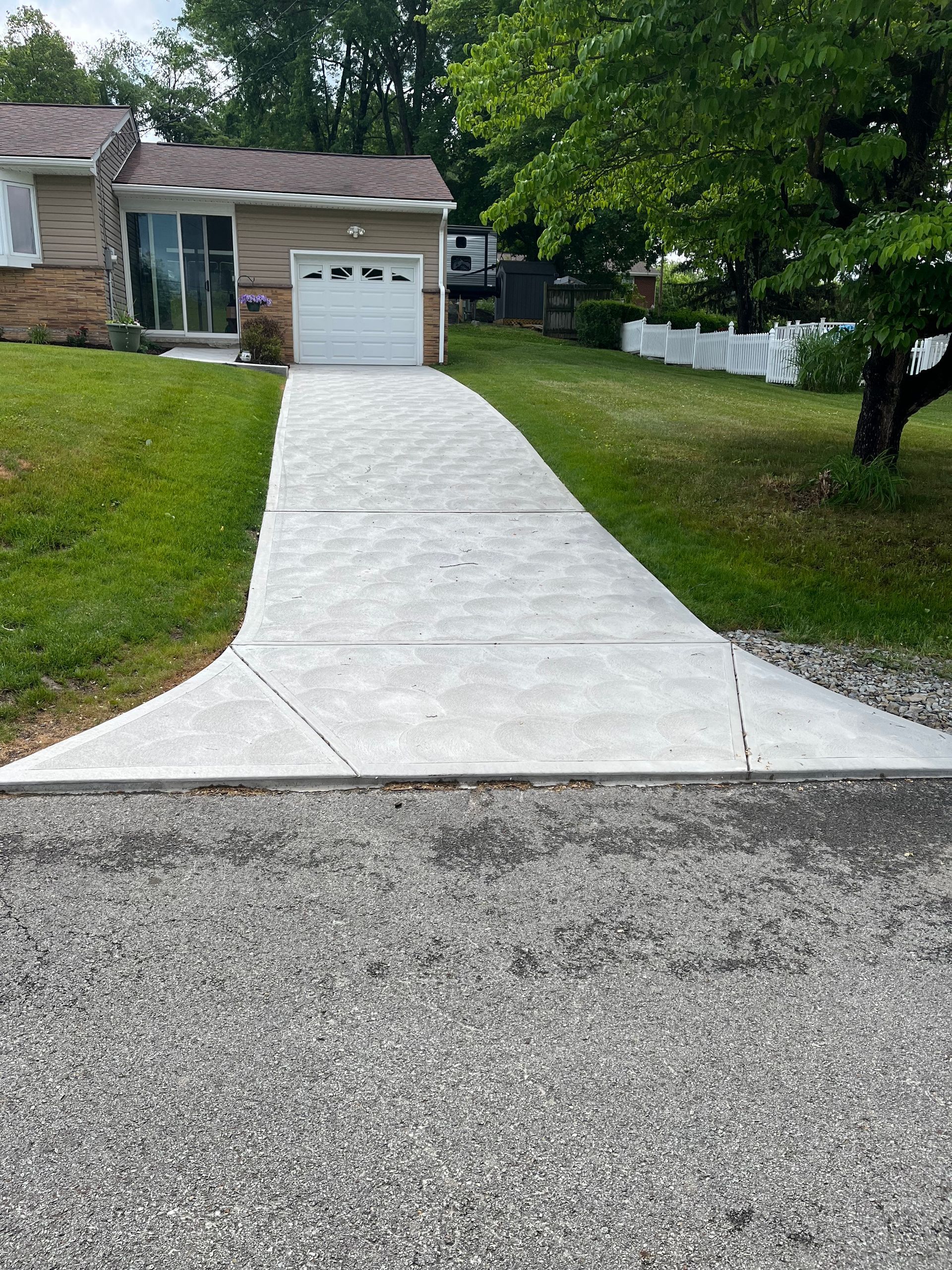 A concrete driveway leading to a house with a garage door.