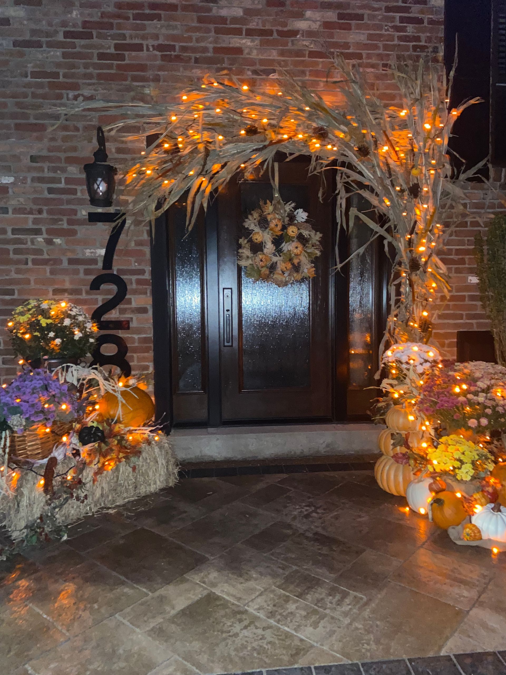 A front door decorated for halloween with pumpkins and lights.