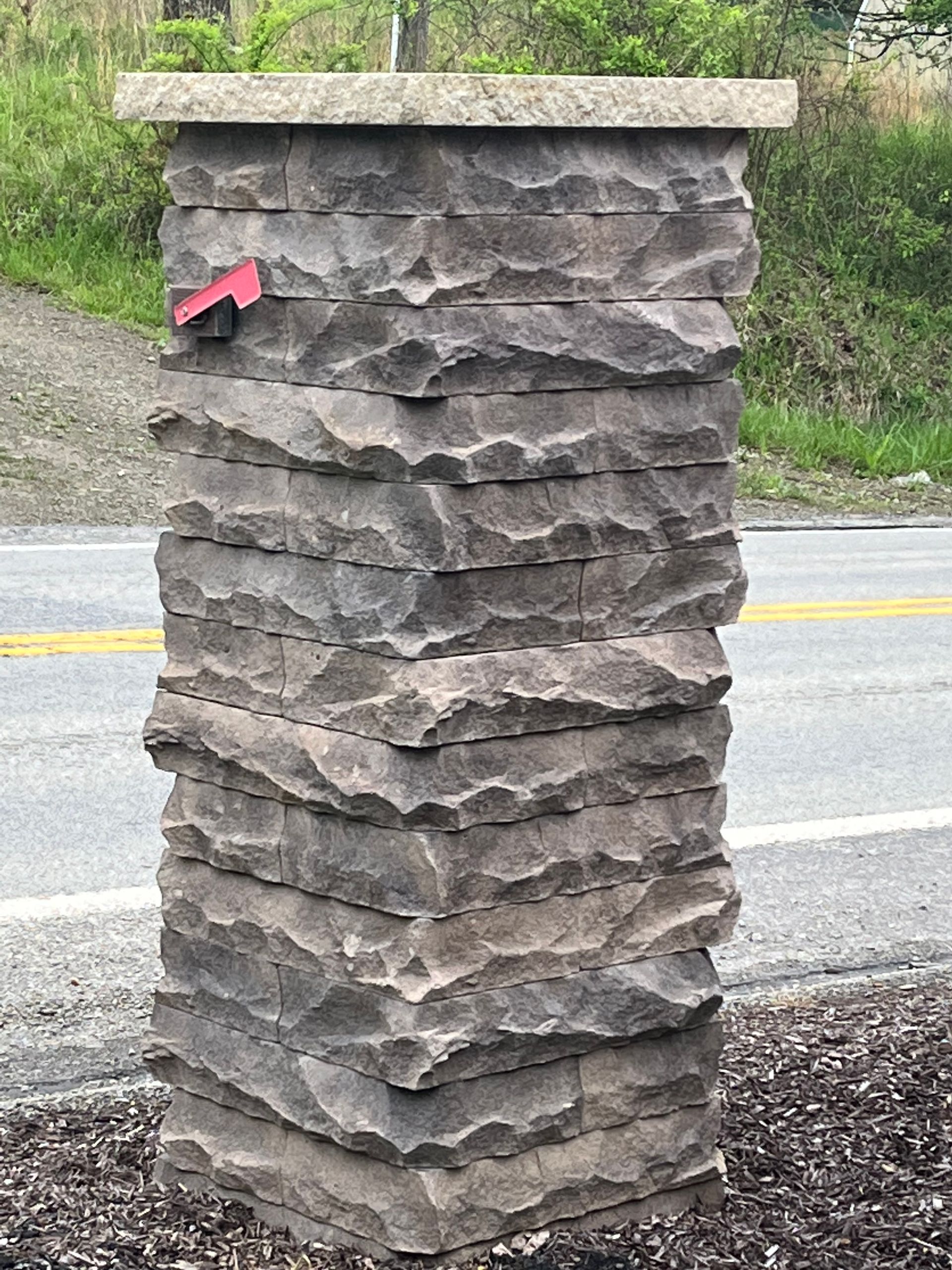 A large stone pillar is sitting next to a road.