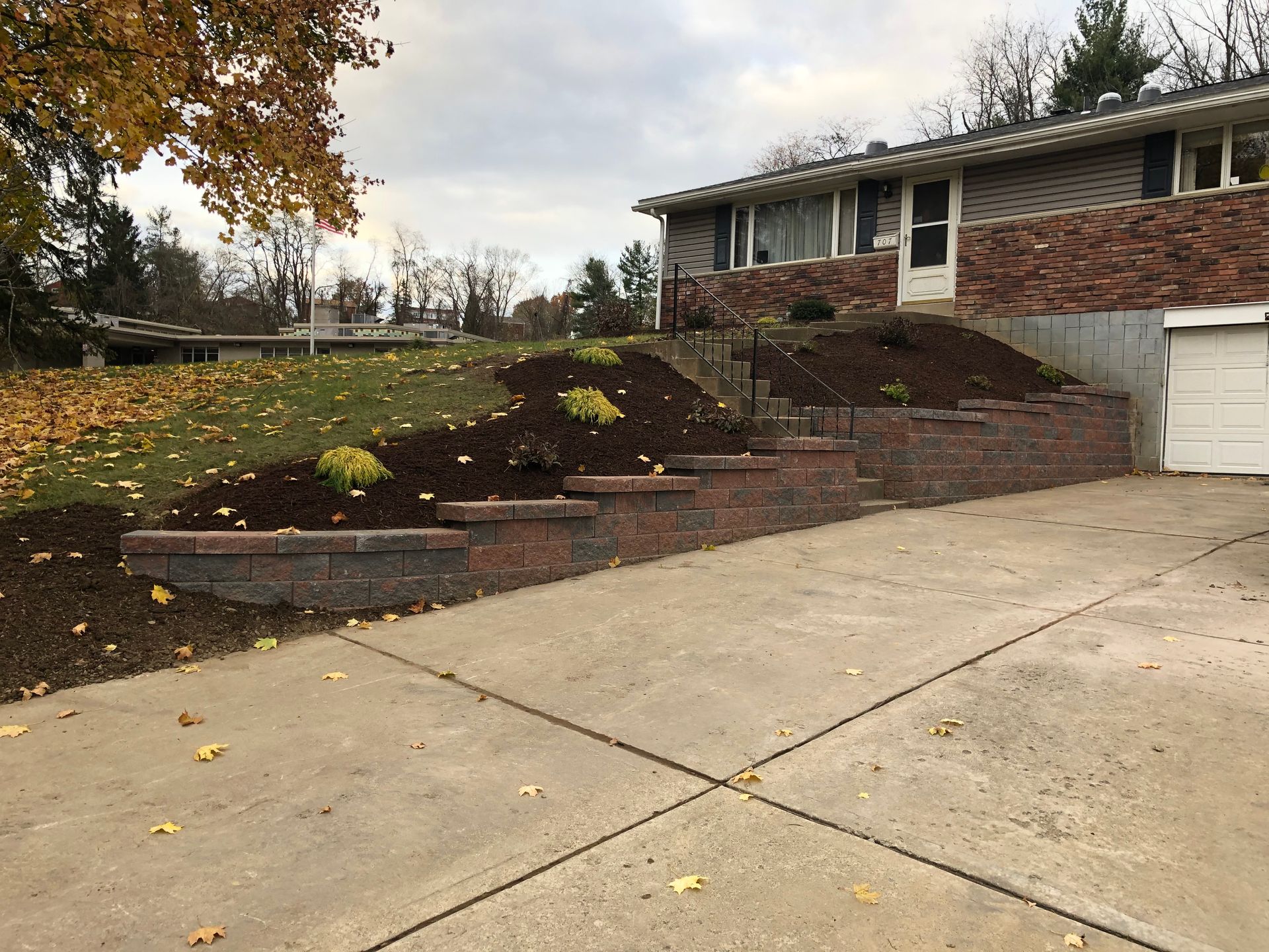 A driveway leading to a house with a brick wall and a garage.